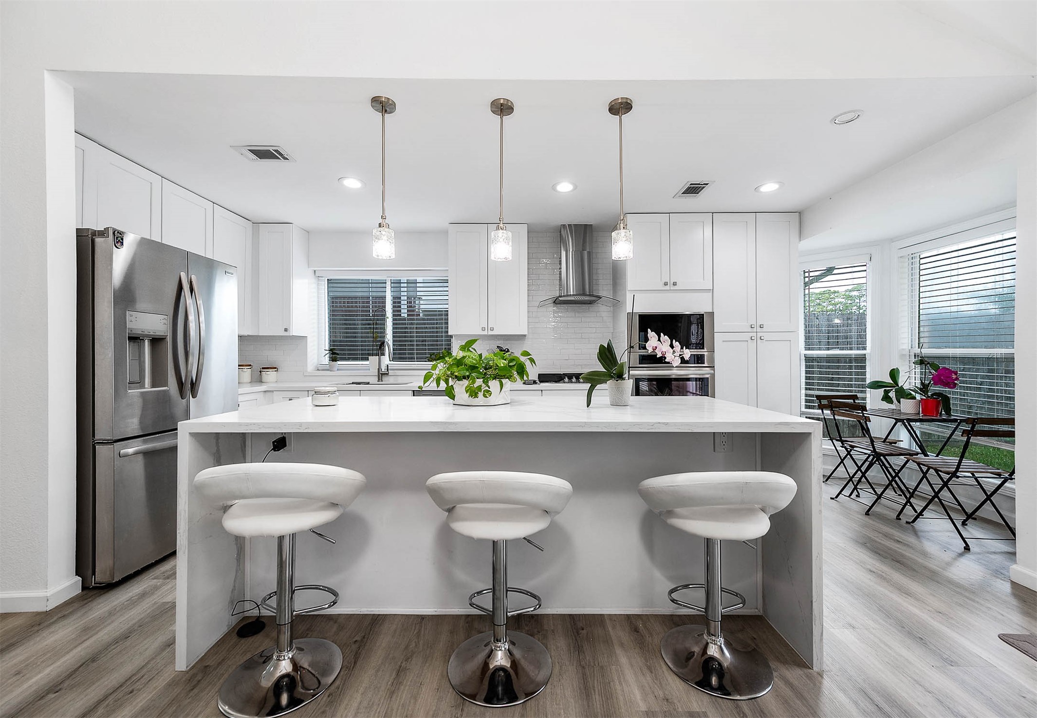 This spacious kitchen features large
windows, white cabinets, SS
appliances, modern tile backsplash,
recessed lighting, and kitchen island
with breakfast bar!