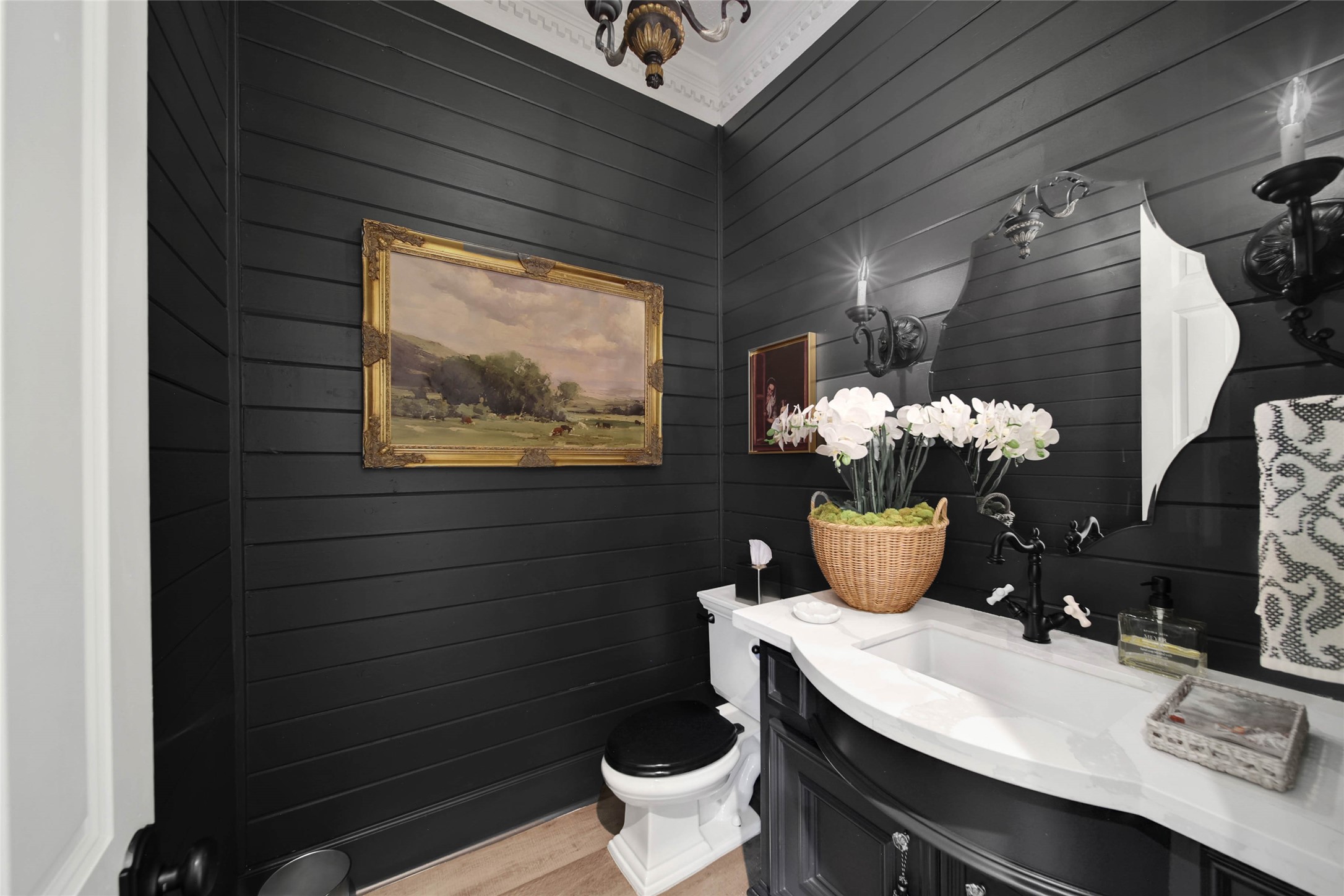 Elegantly styled powder room featuring dark paneling, sophisticated fixtures, and tasteful decor for a touch of luxury.