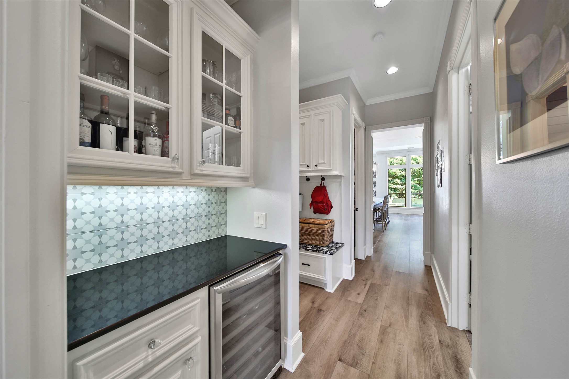 Luxurious butlers pantry hallway with elegant cabinetry, wine storage, and stylish backsplash.
