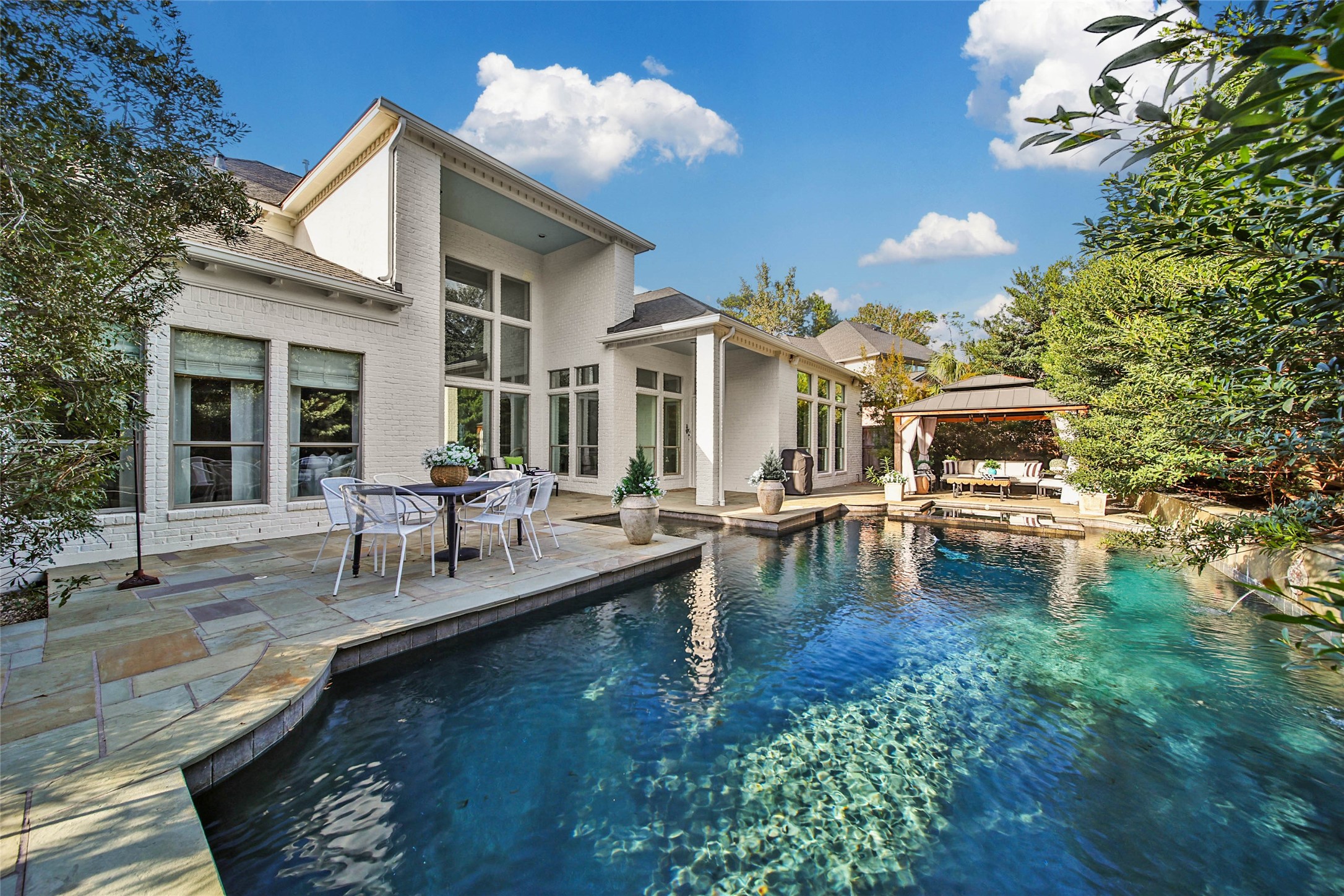 Backyard oasis featuring a sparkling pool, elegant patio area, and a cozy outdoor lounge, perfect for relaxation and entertaining.