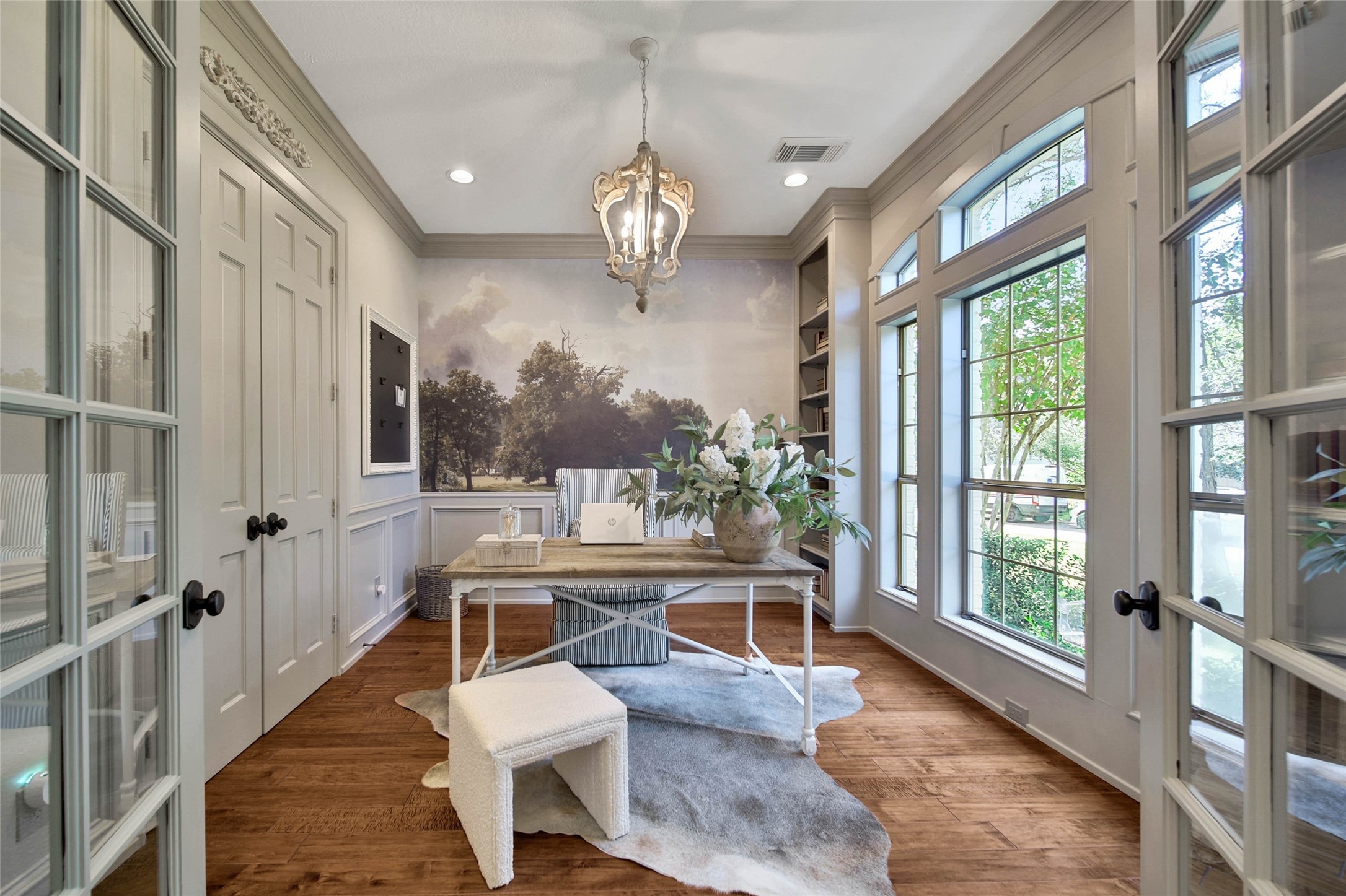 Elegant study bathed in natural light features floor-to-ceiling windows, and exquisite wood flooring, creating an inspiring workspace.