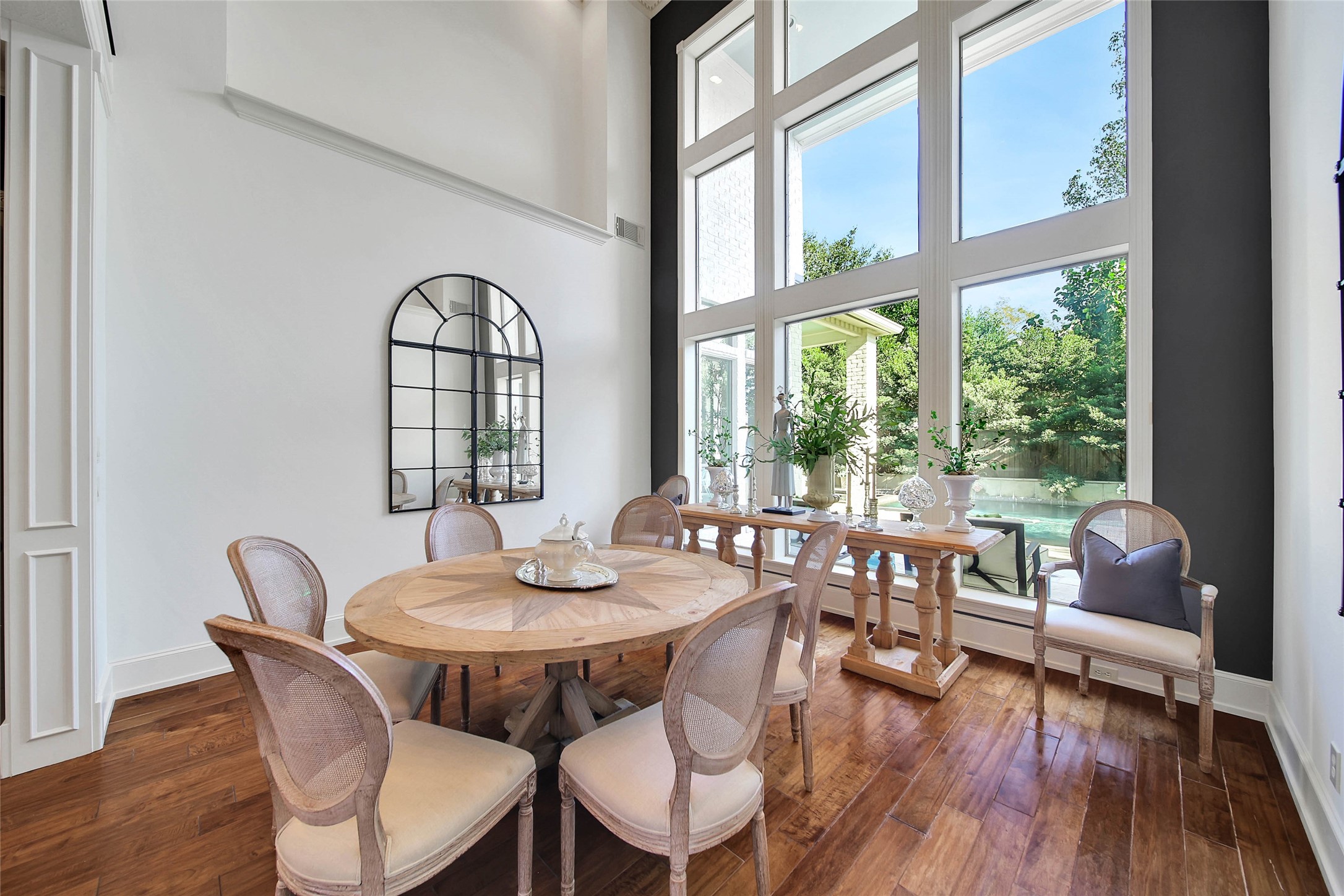 Bright and inviting dining room featuring soaring windows that flood the space with natural light and offer serene garden views.