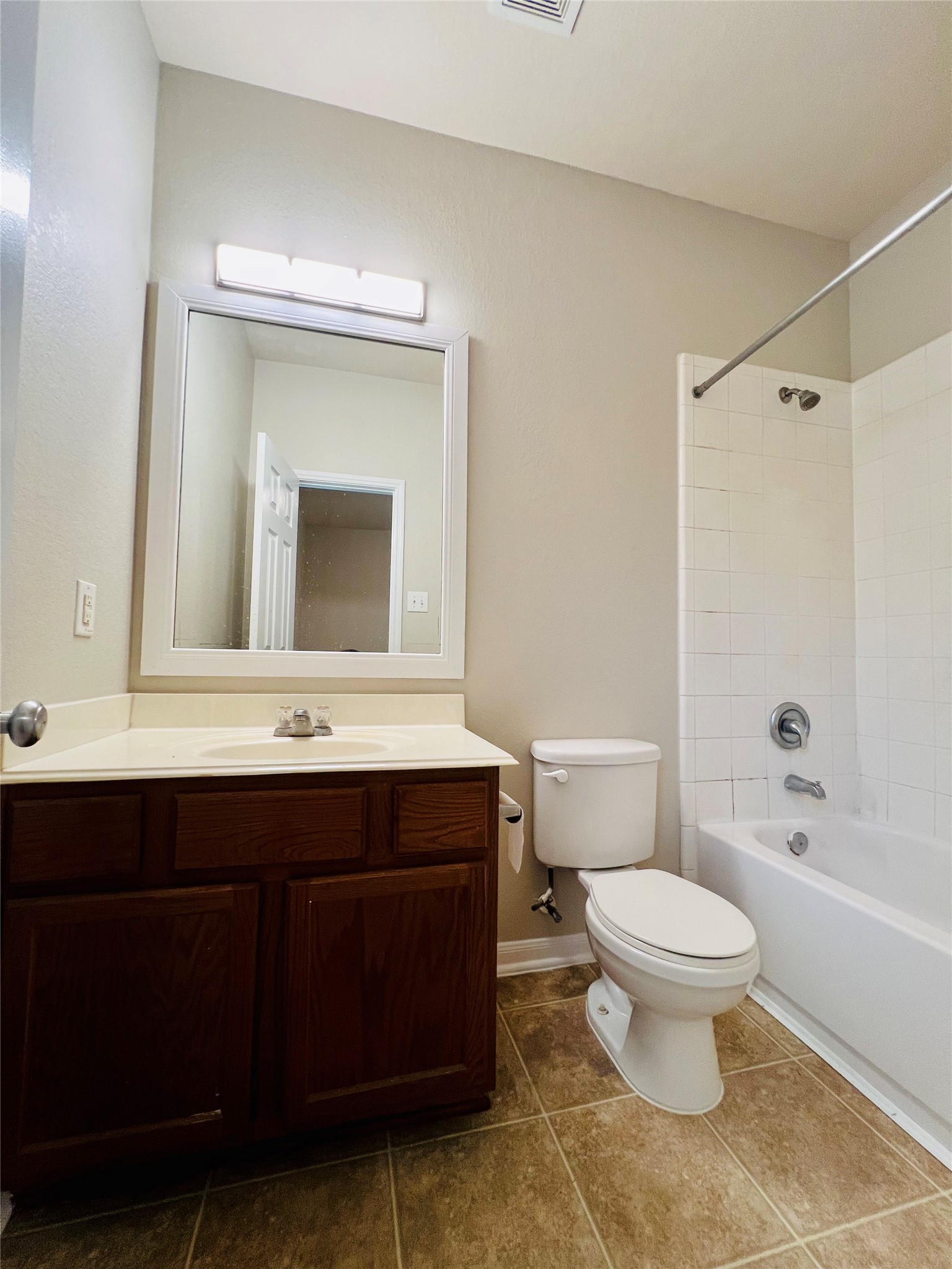 Bright bathroom featuring a sleek vanity with ample storage, a modern mirror with integrated lighting, and a classic shower-tub combo with white tile surround.