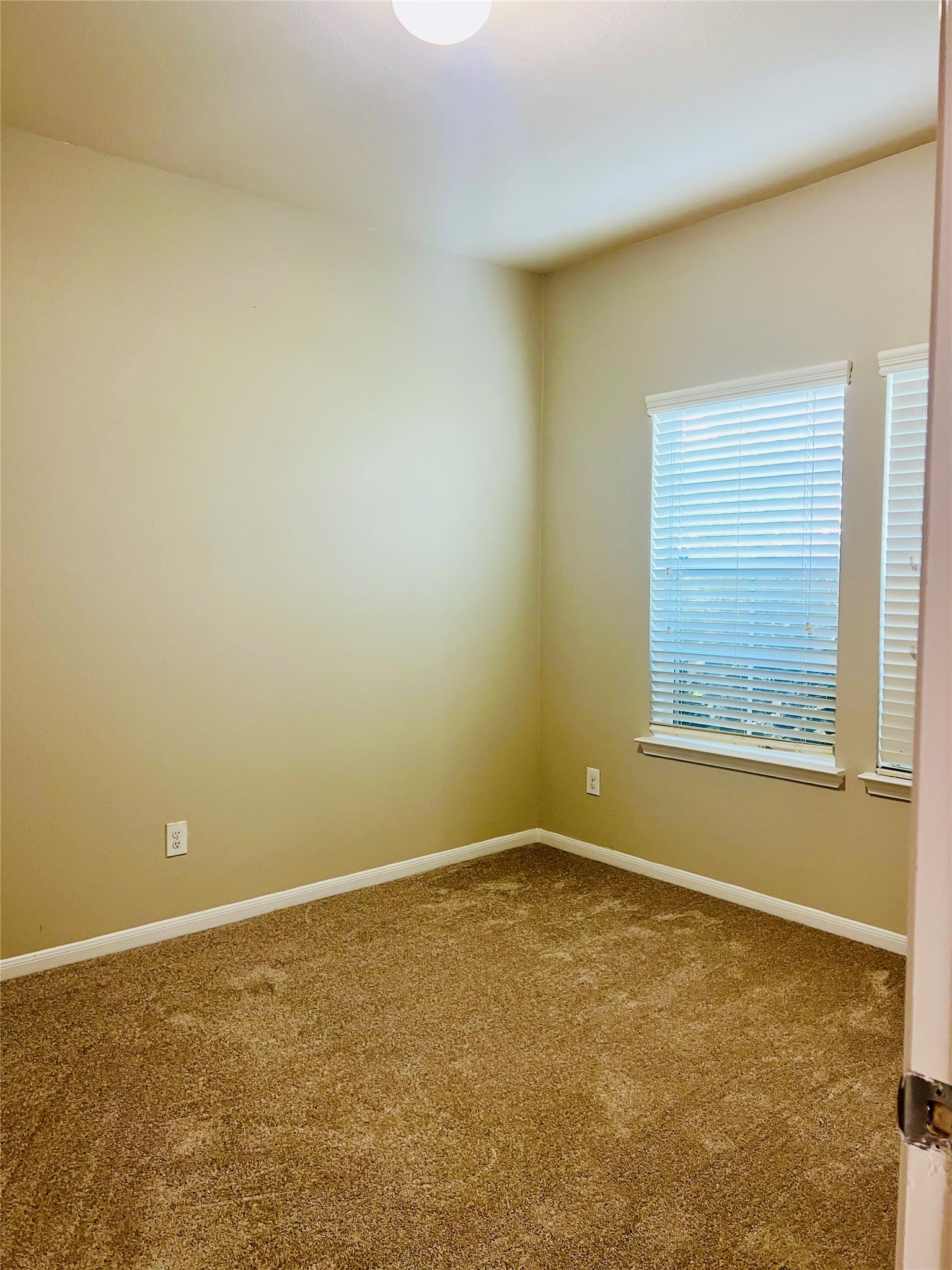 Cozy bedroom with soft carpet flooring, neutral walls, and a window that invites natural light.