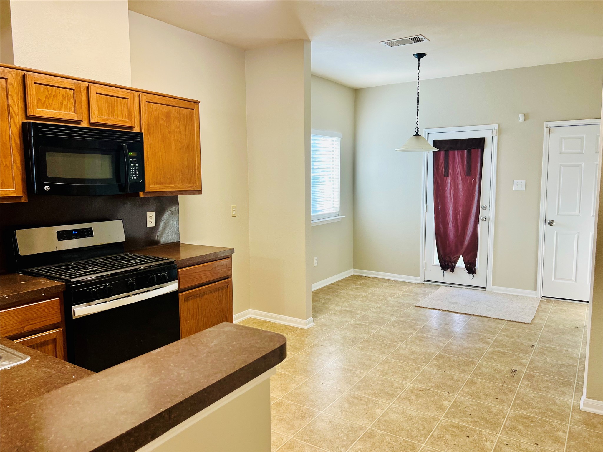 Bright kitchen and dining area with warm wood cabinetry, modern appliances, and a cozy nook leading to the backyard.