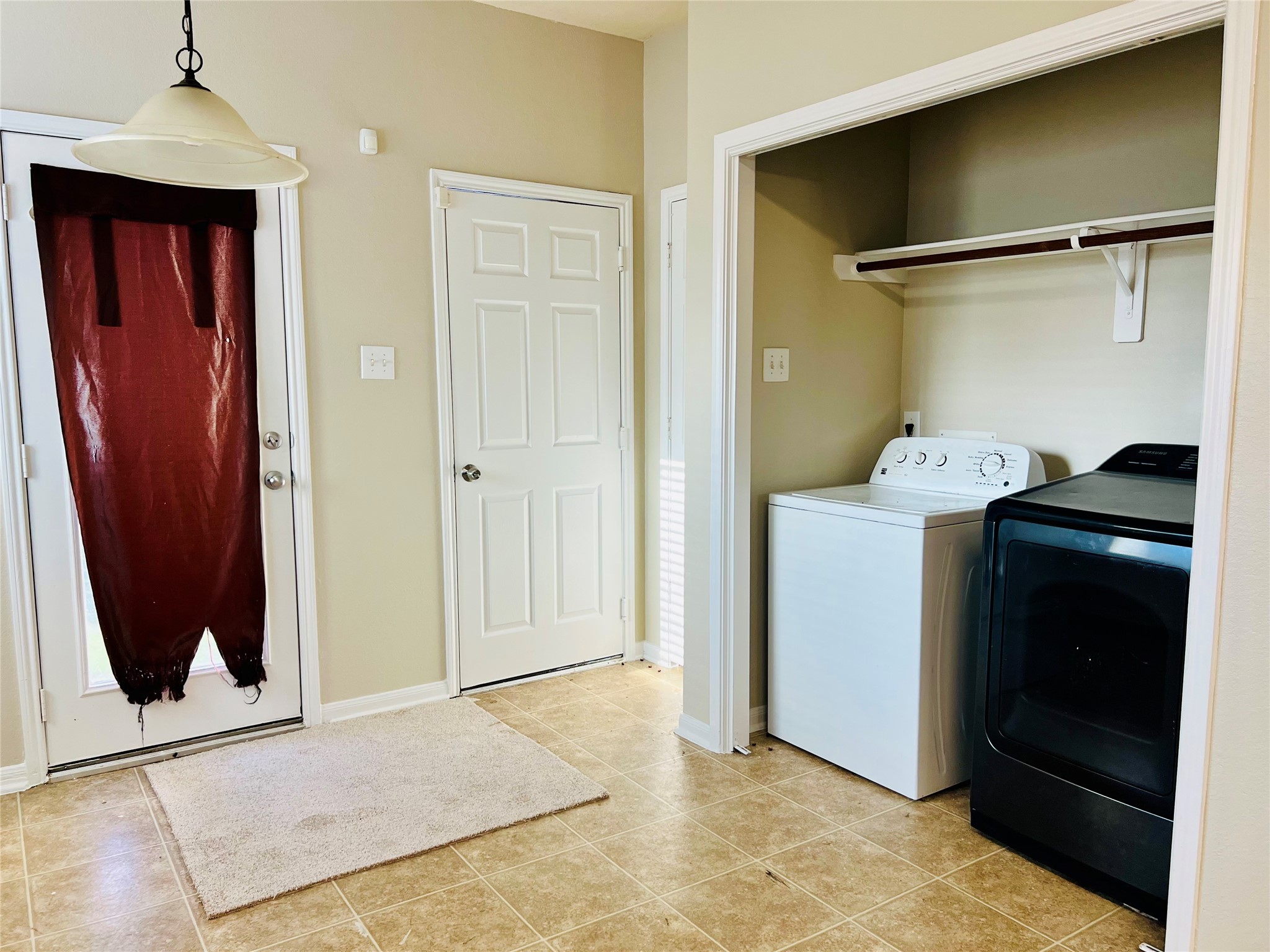 Bright and functional laundry room with modern washer and dryer, convenient shelving, and access to the outdoors.