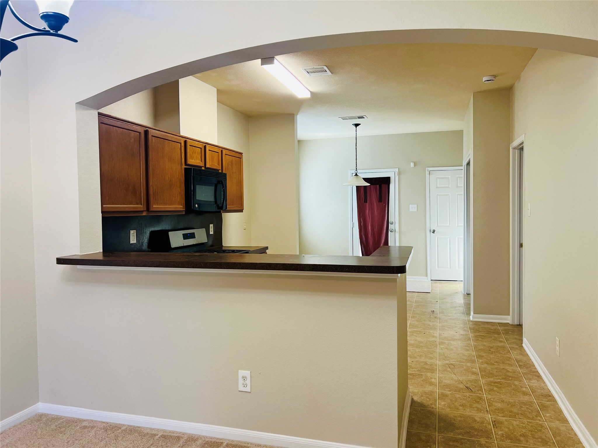 Charming open-concept kitchen with a convenient breakfast bar, featuring warm wood cabinetry, modern appliances, and a cozy adjoining dining area with tile flooring.