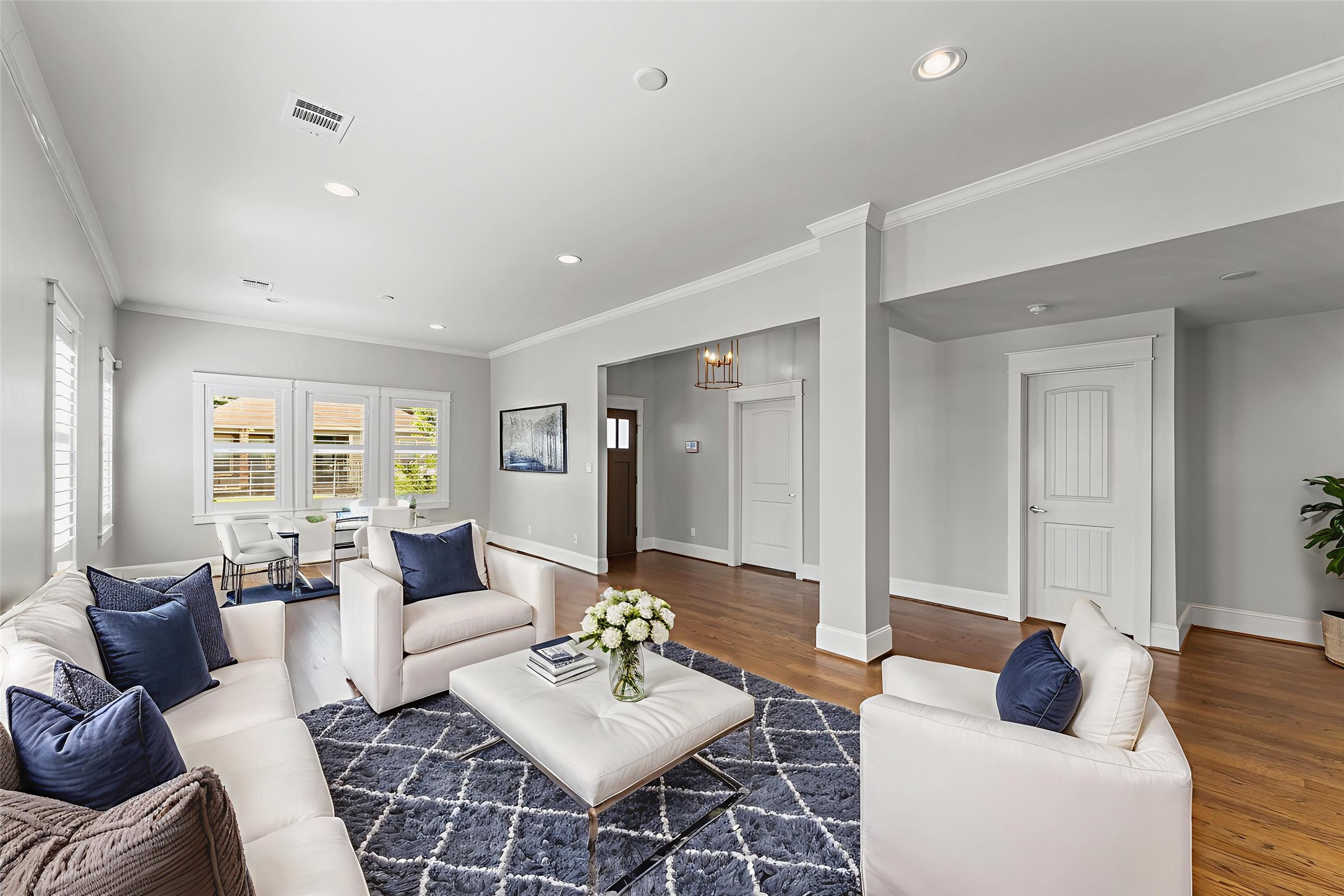 This inviting living room features an open layout with abundant natural light. Hardwood floors and light gray walls provide a modern touch, while large windows offer a view outside.