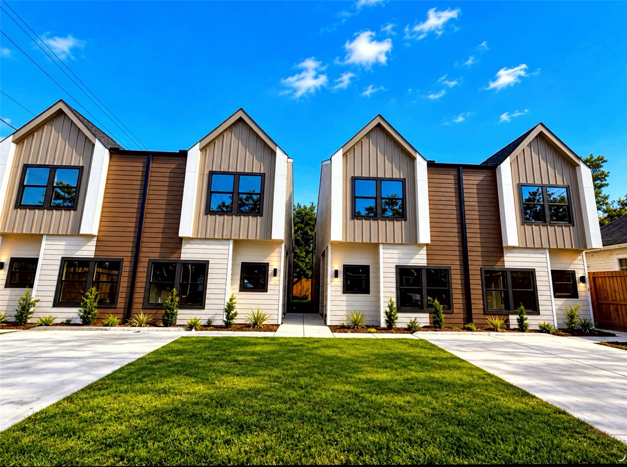 Modern duplexes with striking gabled roofs, featuring a clean, contemporary facade in neutral tones. A spacious driveway and neatly landscaped front yard offer excellent curb appeal.