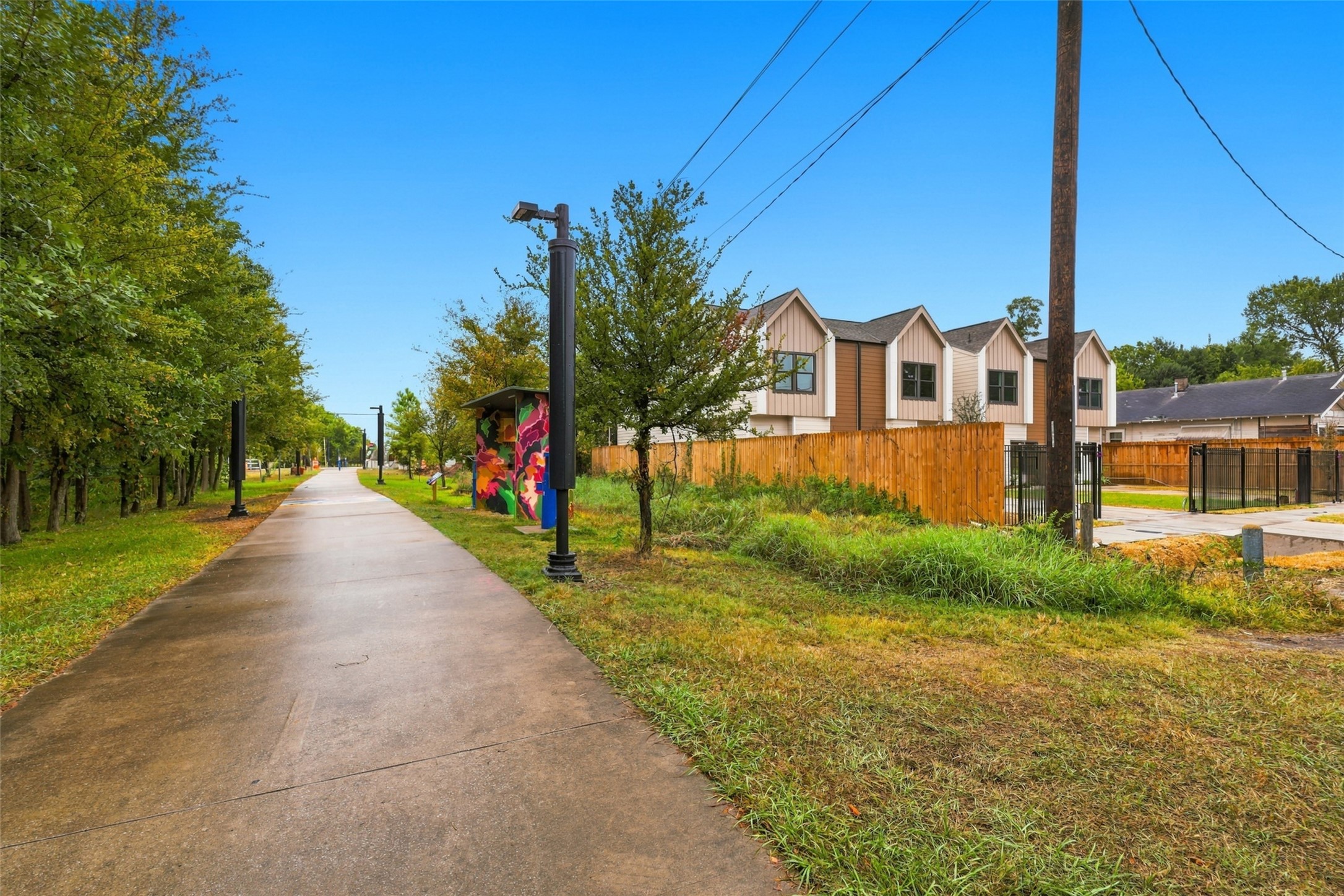 Charming area with modern homes adjacent to a scenic walking path- The Columbia Tap- lined with trees and vibrant street art.