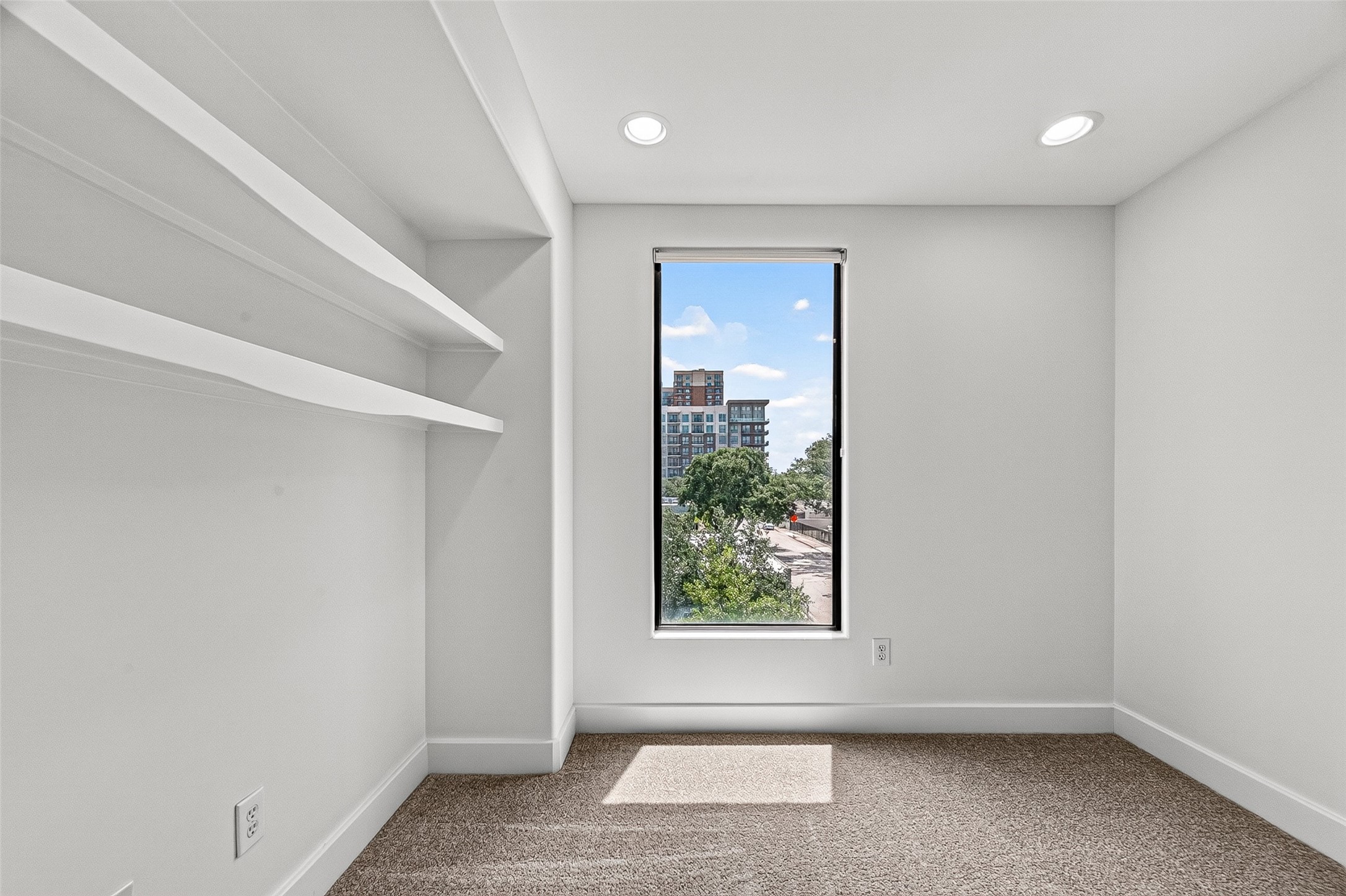 Bright and cozy flex space on third floor featuring built-in shelving and large windows, perfect for a home office or reading nook.