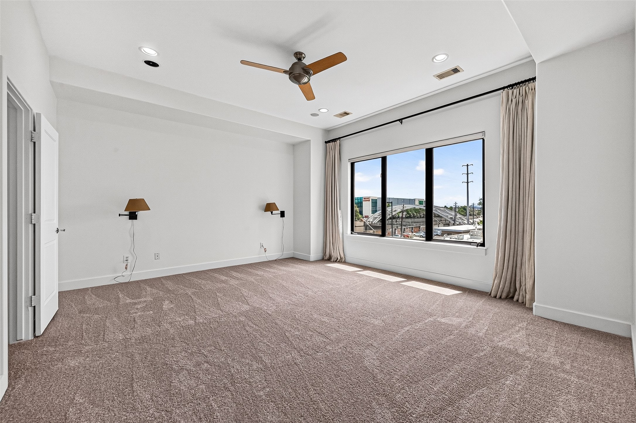 Spacious primary bedroom with plush carpeting, large window offering ample natural light, perfect for relaxation.