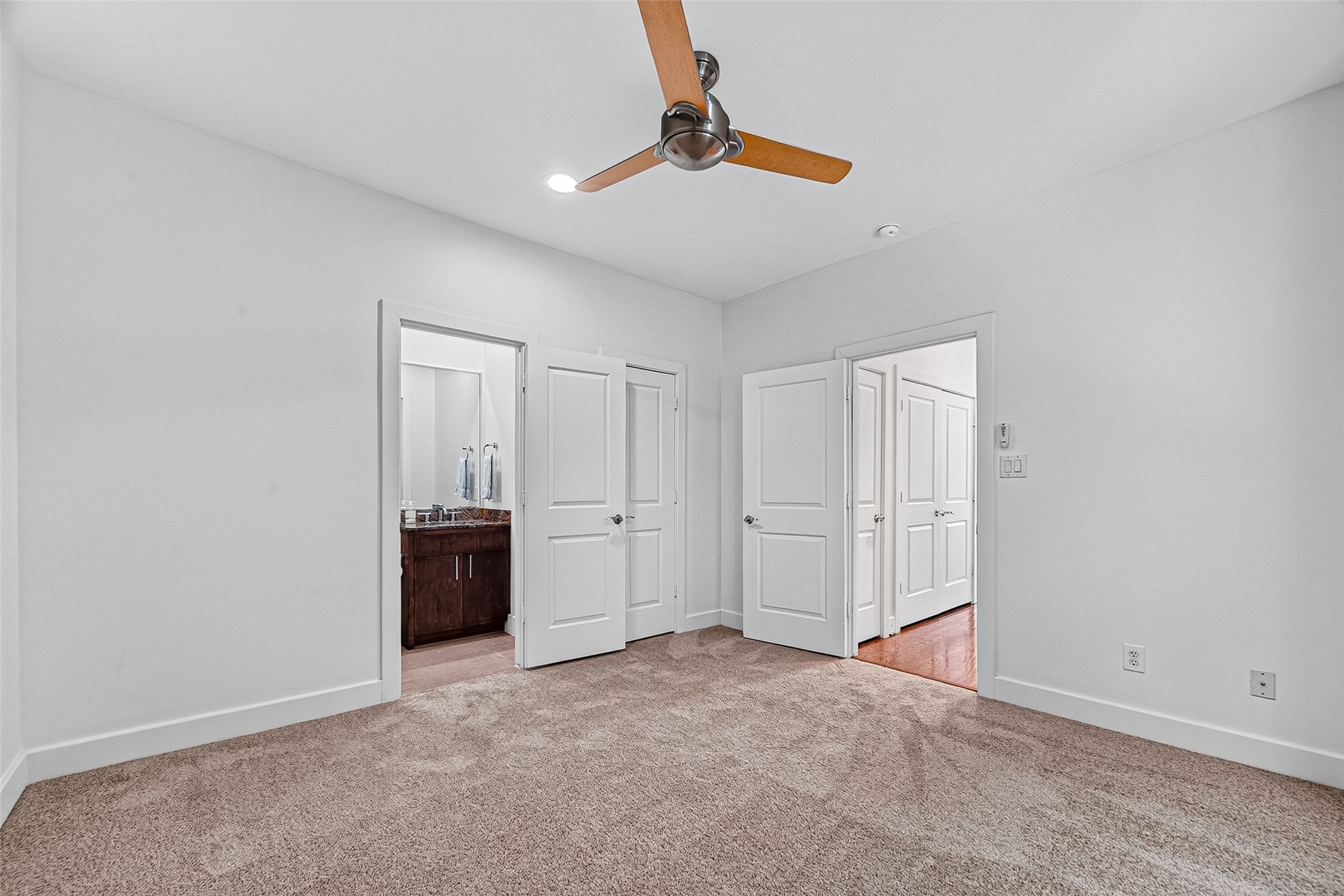 Spacious bedroom on third floor with plush carpeting, a modern ceiling fan, walk-in closet, and easy access to an en-suite bathroom.