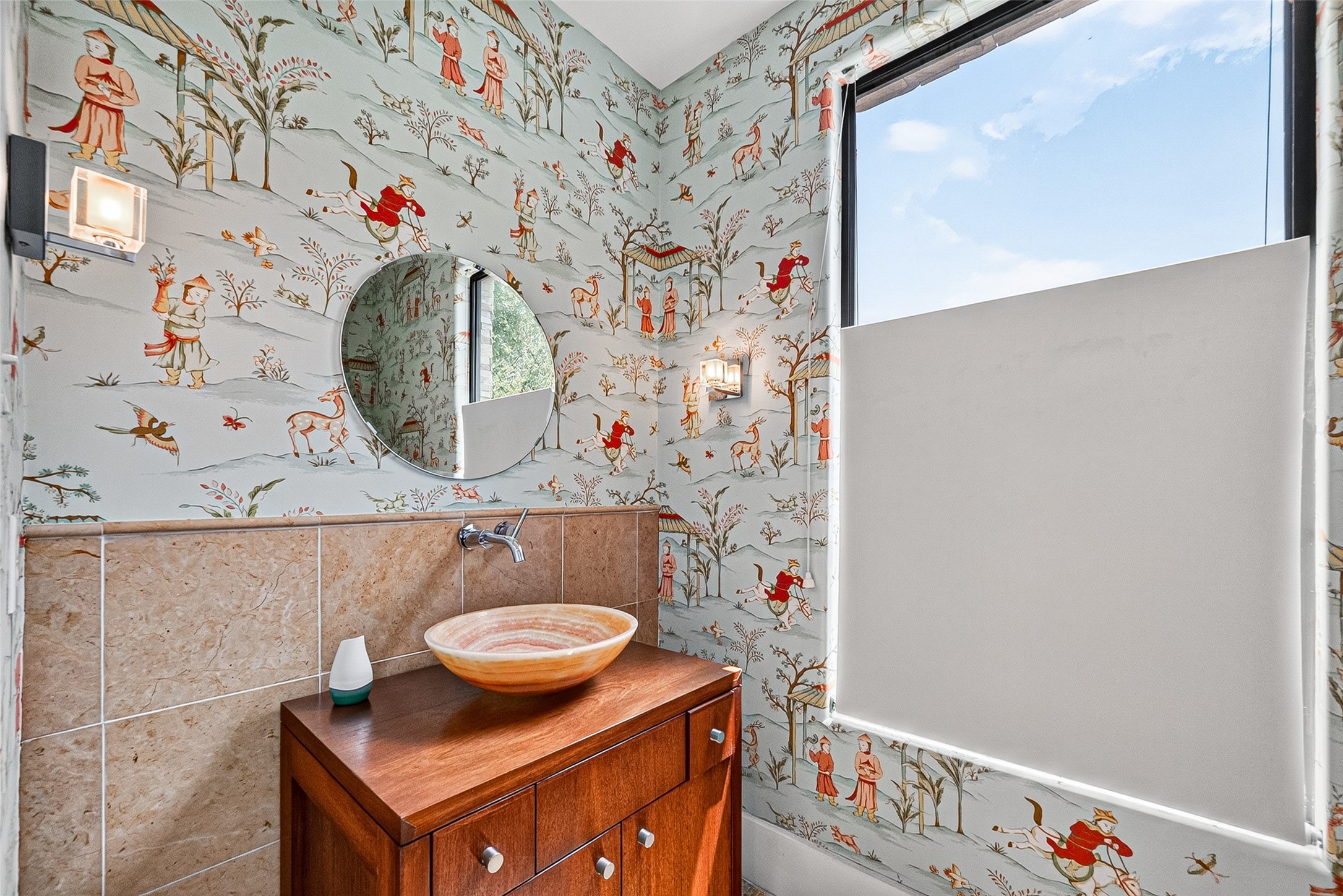 Charming half bathroom featuring whimsical wallpaper, a modern vessel sink, and abundant natural light through a large window.