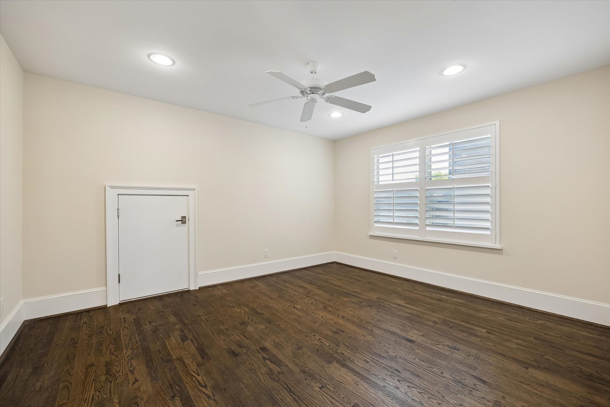 Third bedroom with hardwood floors, wood shutters, walk-in closet and ceiling fan.
