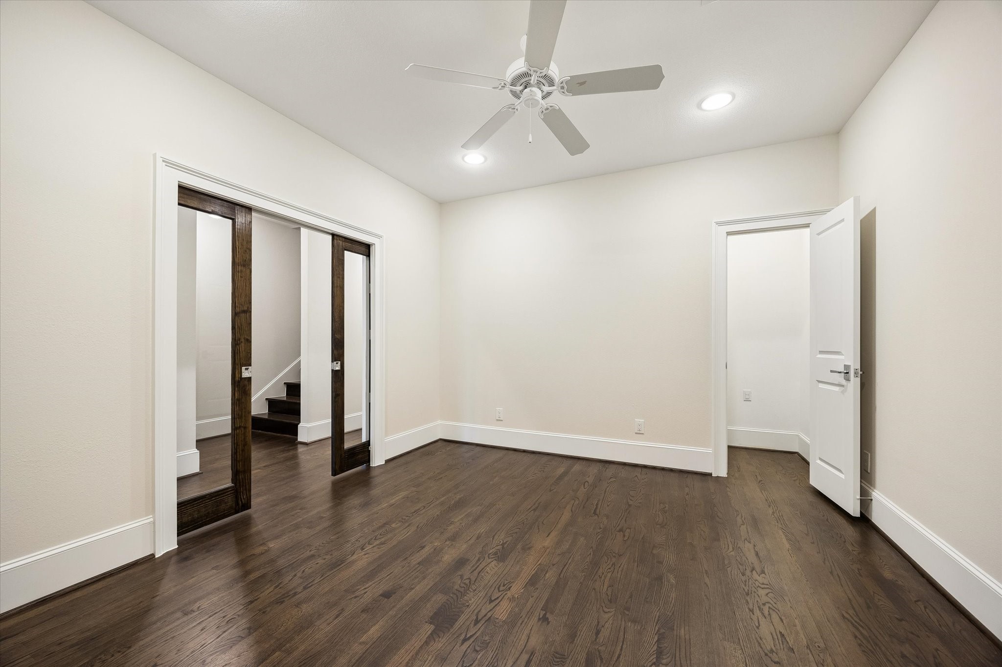 Spacious home office with pocket doors, hardwood floors, a closet, and access to a full bathroom.