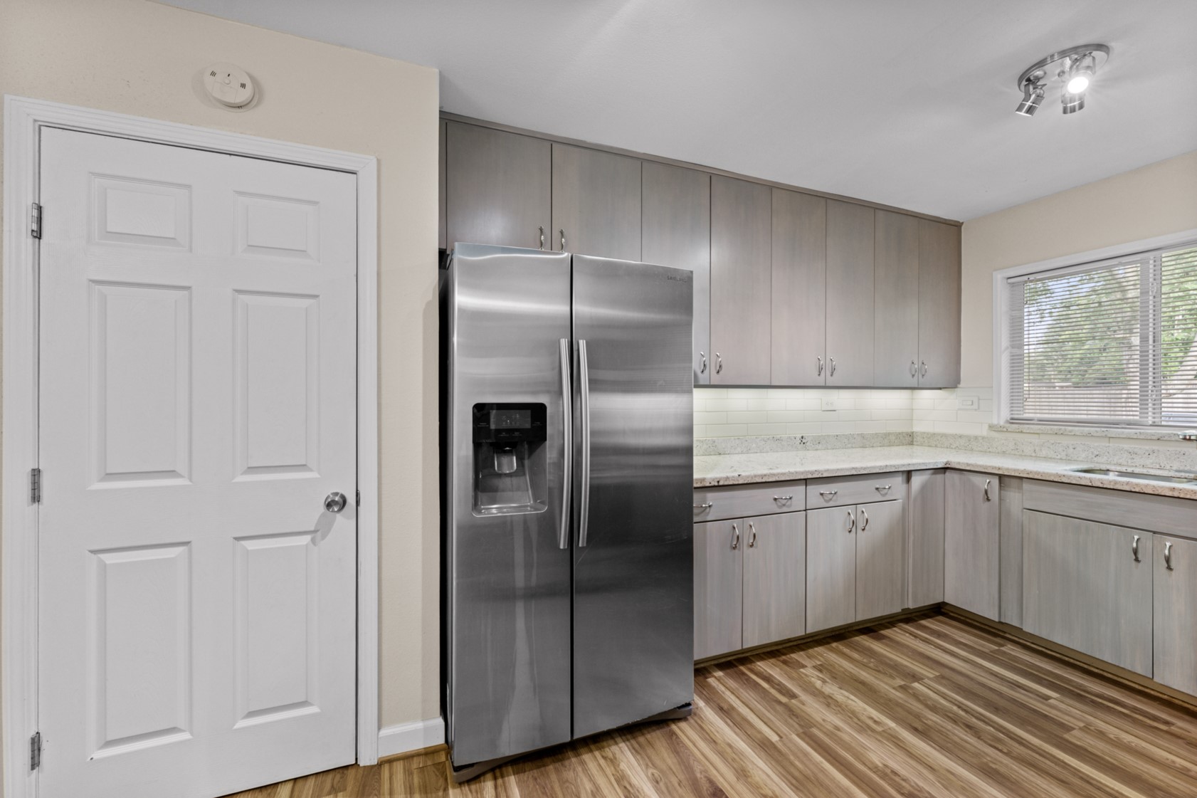 The updated kitchen also features a crisp, white subway tile backsplash and a PANTRY (door on the left). Under-cabinet lighting and granite counters complete this kitchen.