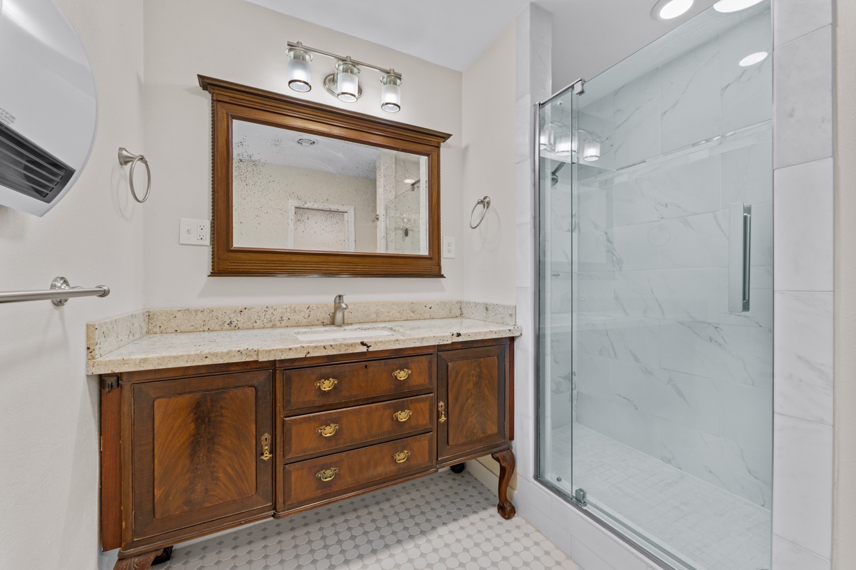 Beautifully refinished furniture pieces were part of this thoughtful redesign and add warmth and character to this bathroom while blending well wih modern finishes. Large walk-in shower!