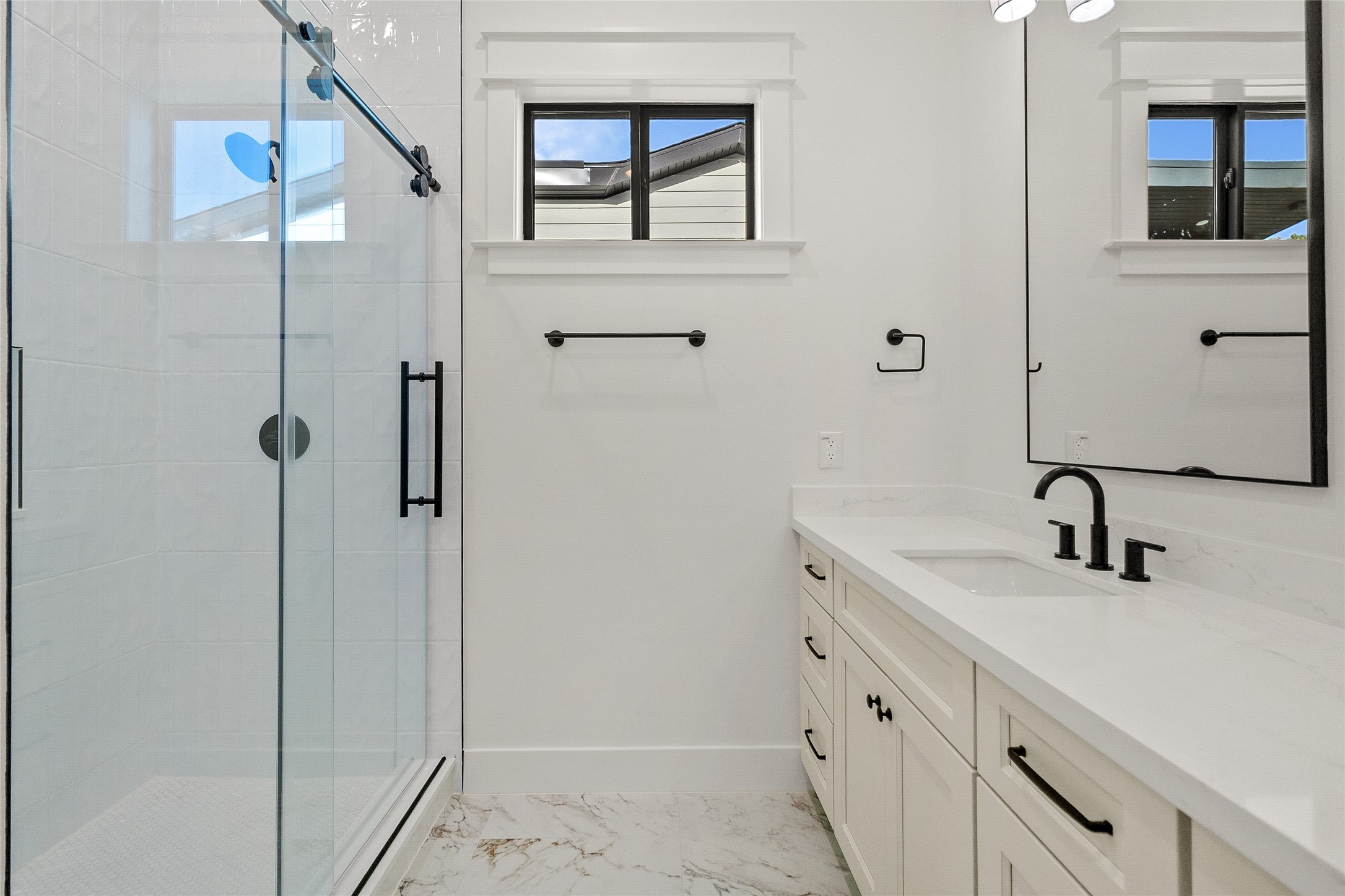 A beautifully finished secondary bathroom features a sleek glass-enclosed shower, quartz vanity, and timeless designer finishes.