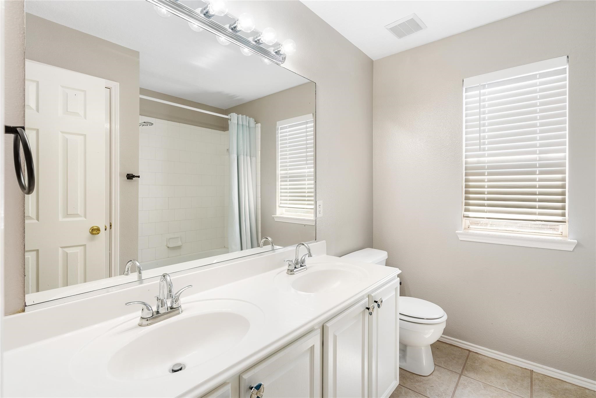 The secondary bathroom is conveniently located next to the bedrooms, and has a dual vanity with plenty of storage space.
