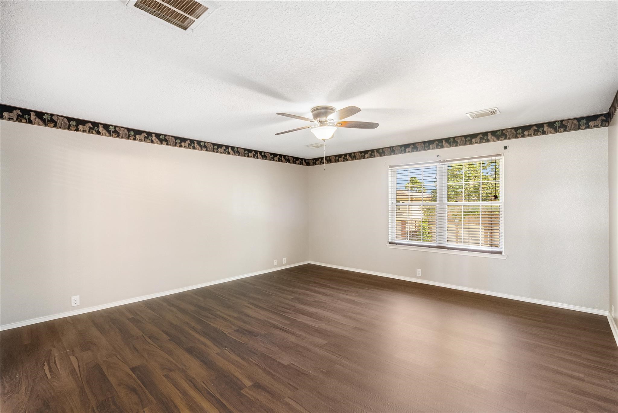 The sprawling primary suite has been freshly painted and is equipped with a ceiling fan and a large, bright window!
