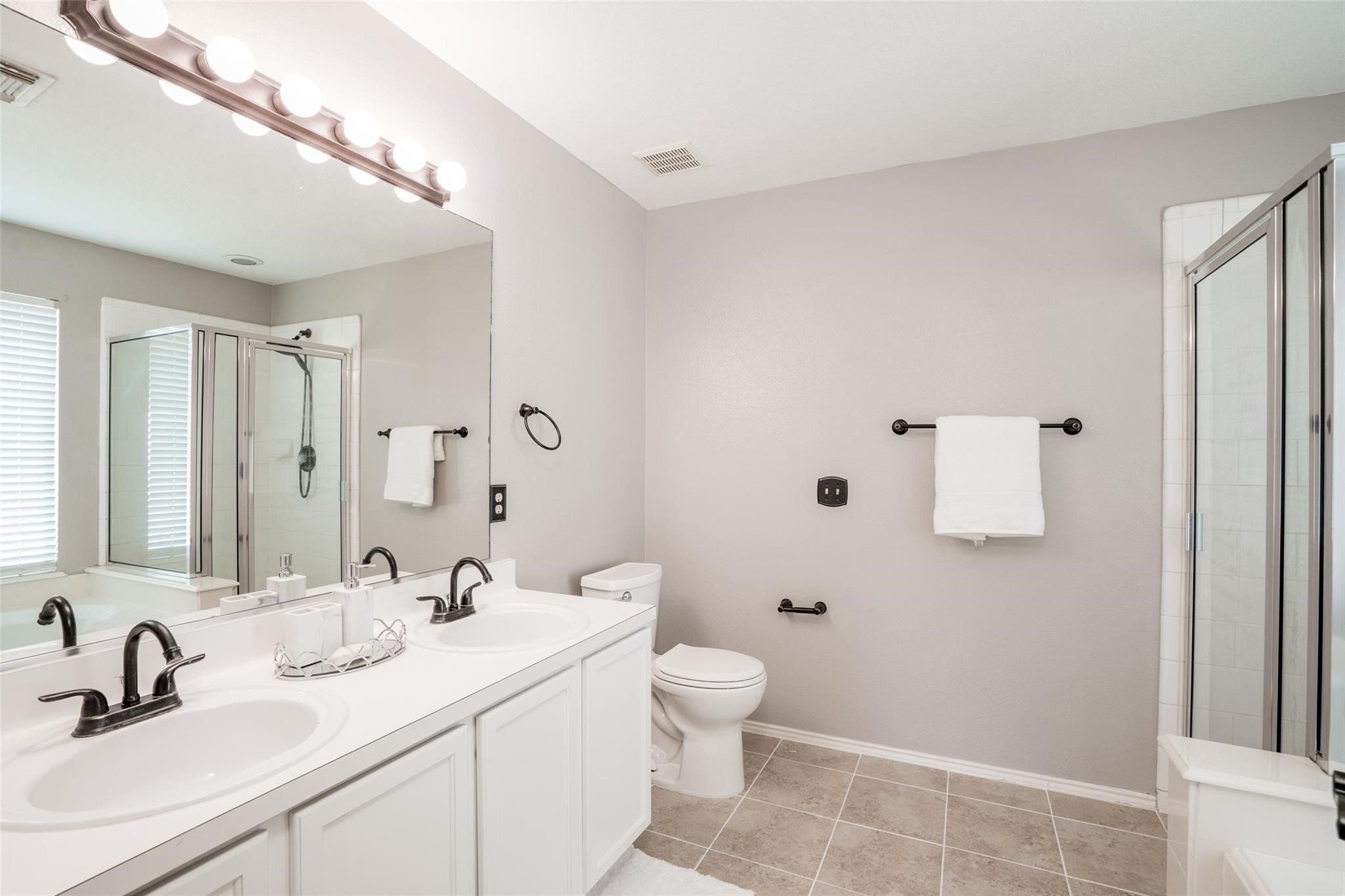 The primary bathroom is a retreat with dual sink vanity, large mirror and ceramic tile