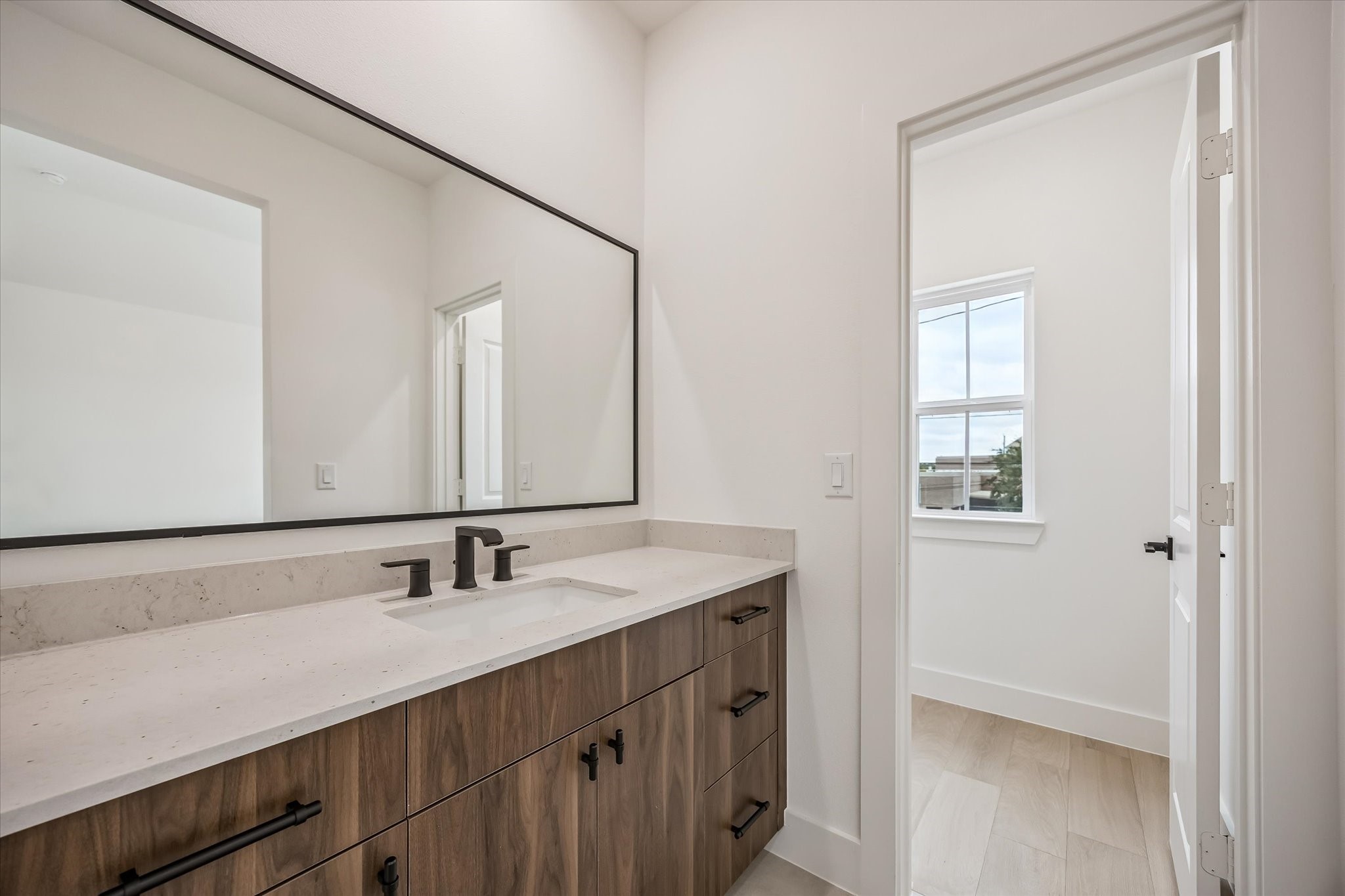 Sleek bathroom featuring a spacious vanity with modern fixtures, elegant wood cabinetry, and a large mirror, offering a bright and airy feel.