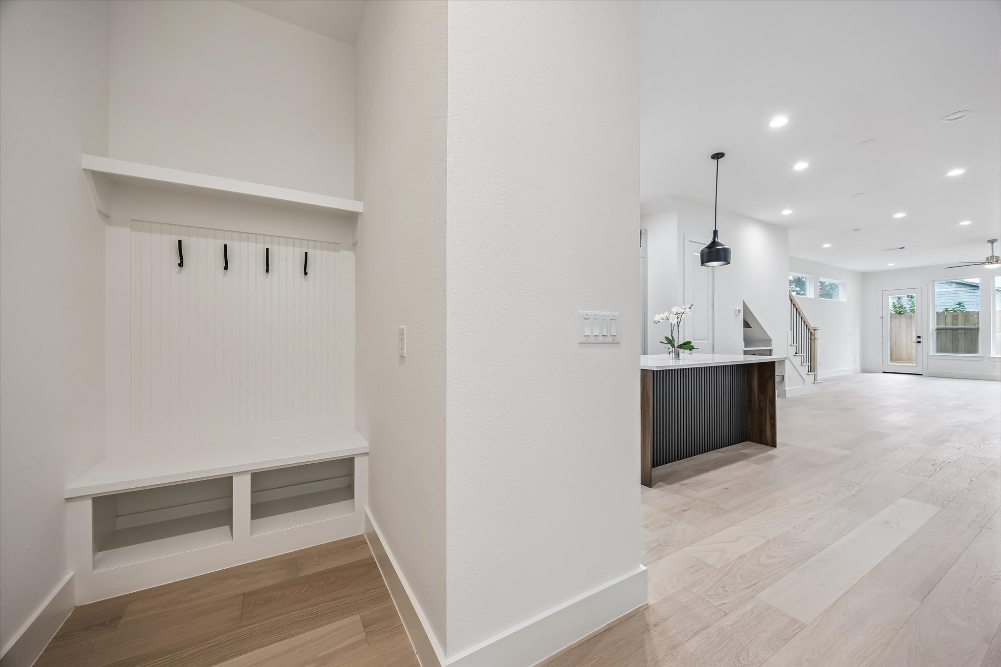 Bright and spacious open-concept living area with sleek light wood flooring, a modern kitchen island, and convenient entryway storage. Bright and spacious open-concept living area with sleek light wood flooring, a modern kitchen island, and convenient entryway storage.