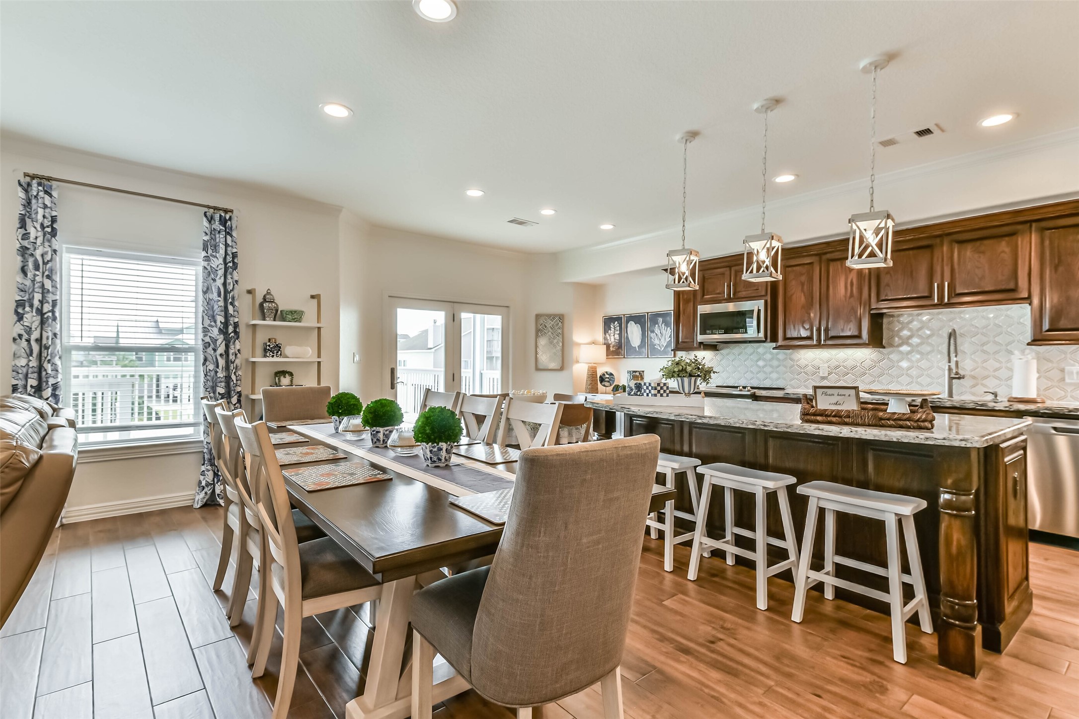 Beautifully styled open kitchen and dining area features coordinated furnishings, island bar seating, and designer lighting, all included with the home for a true turnkey experience.