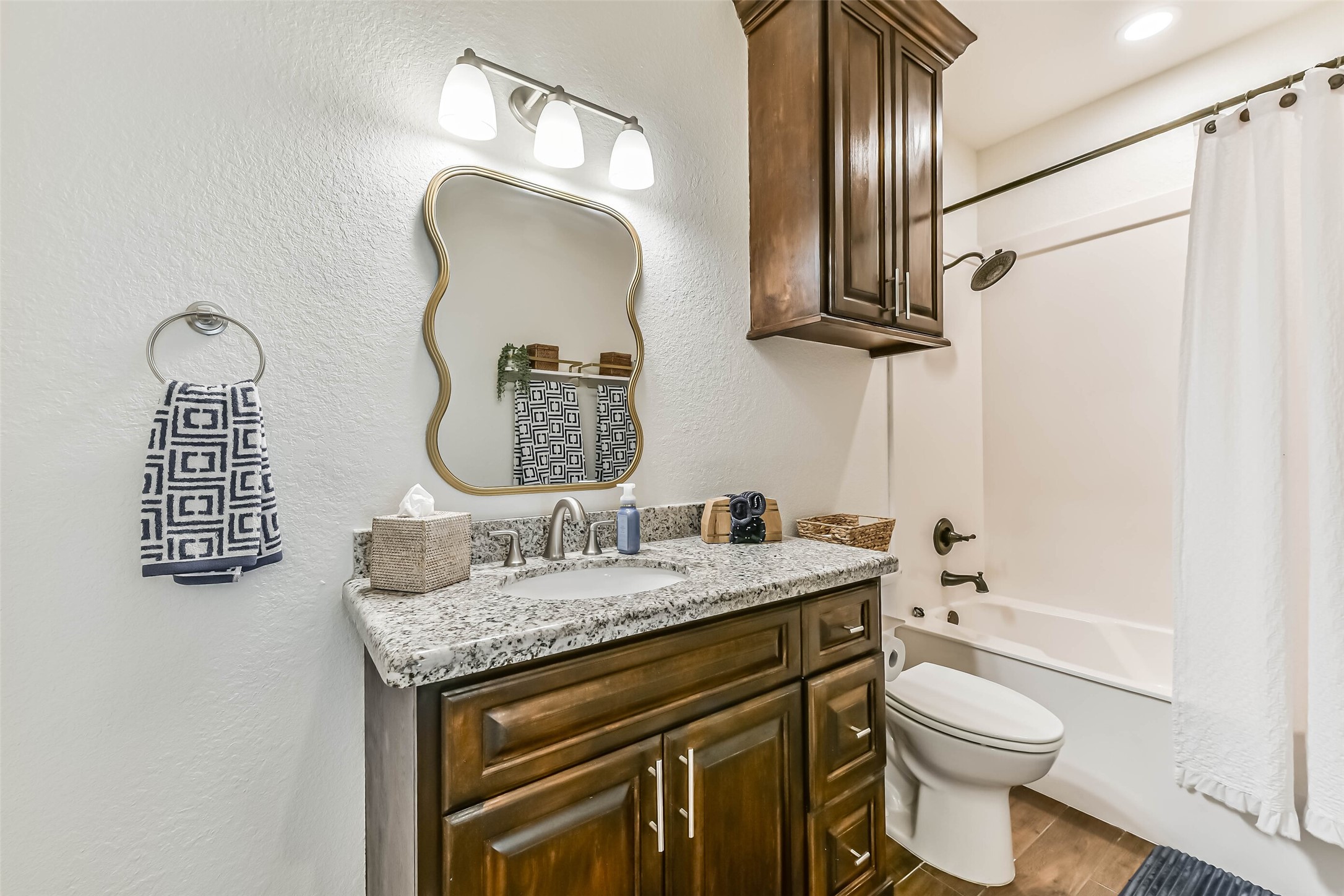 Adjacent bathroom conveniently located features granite vanity, storage cabinetry, and tub-shower combination.