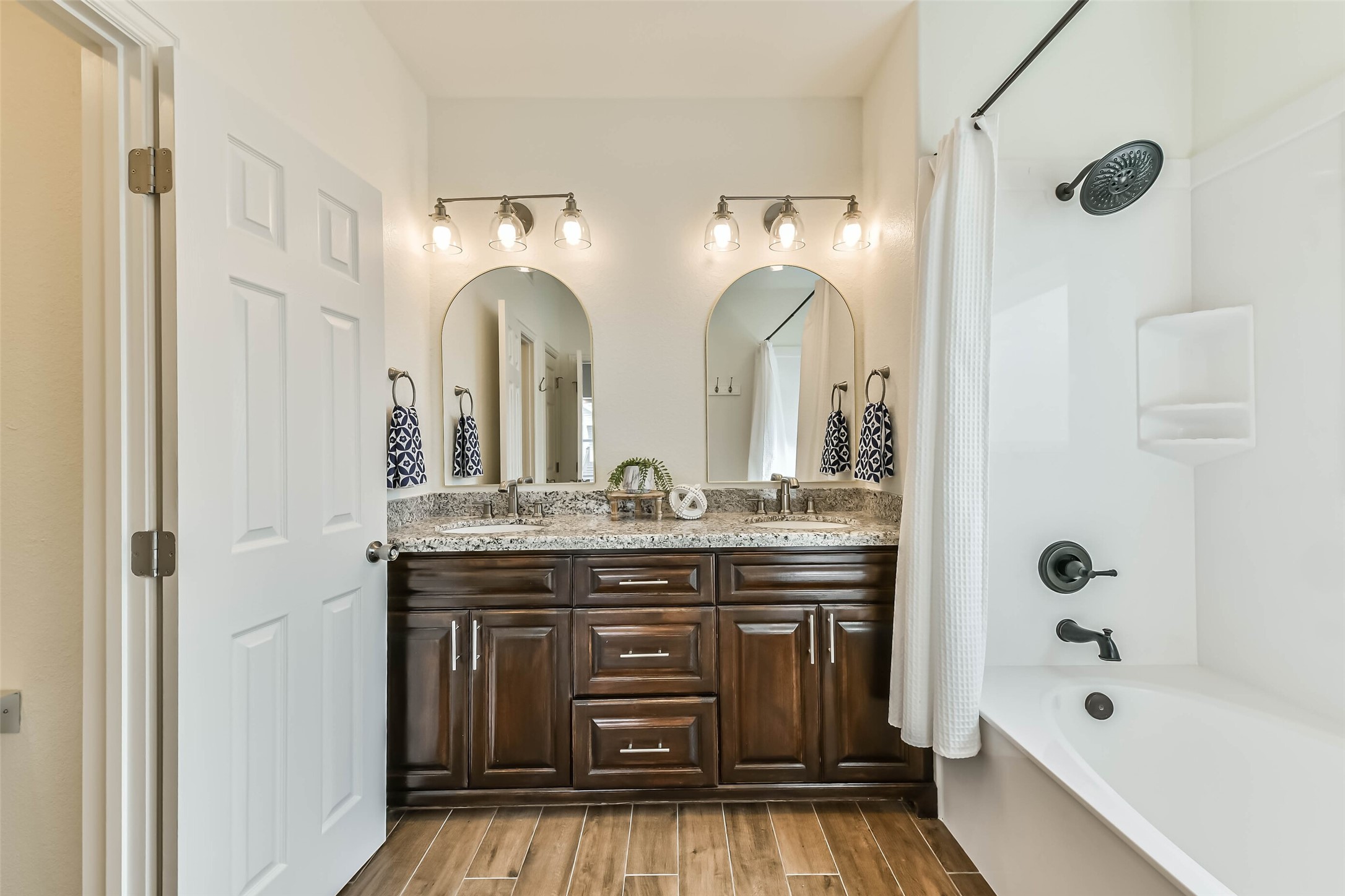 Spacious guest bath features dual sinks, granite countertops, and ample cabinetry for storage and convenience.