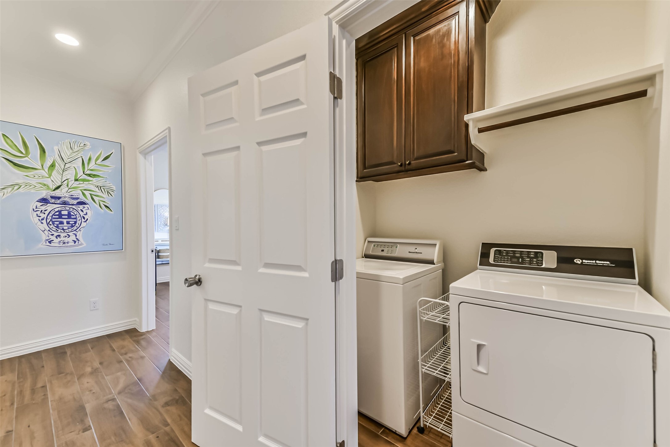 Convenient laundry area featuring full-size washer and dryer connections, upper cabinetry, and additional storage space.