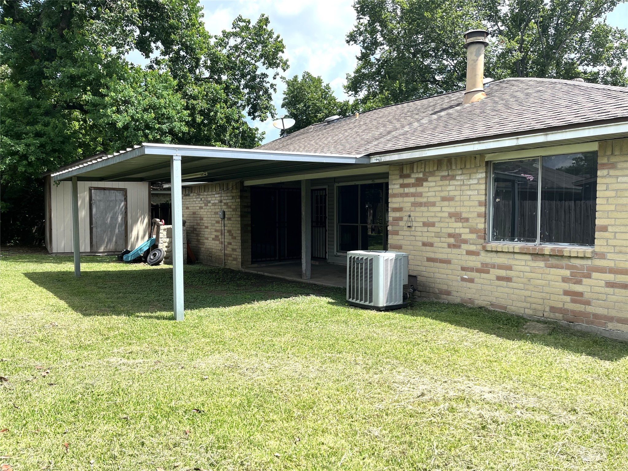 Fenced in backary with covered patio & storage area