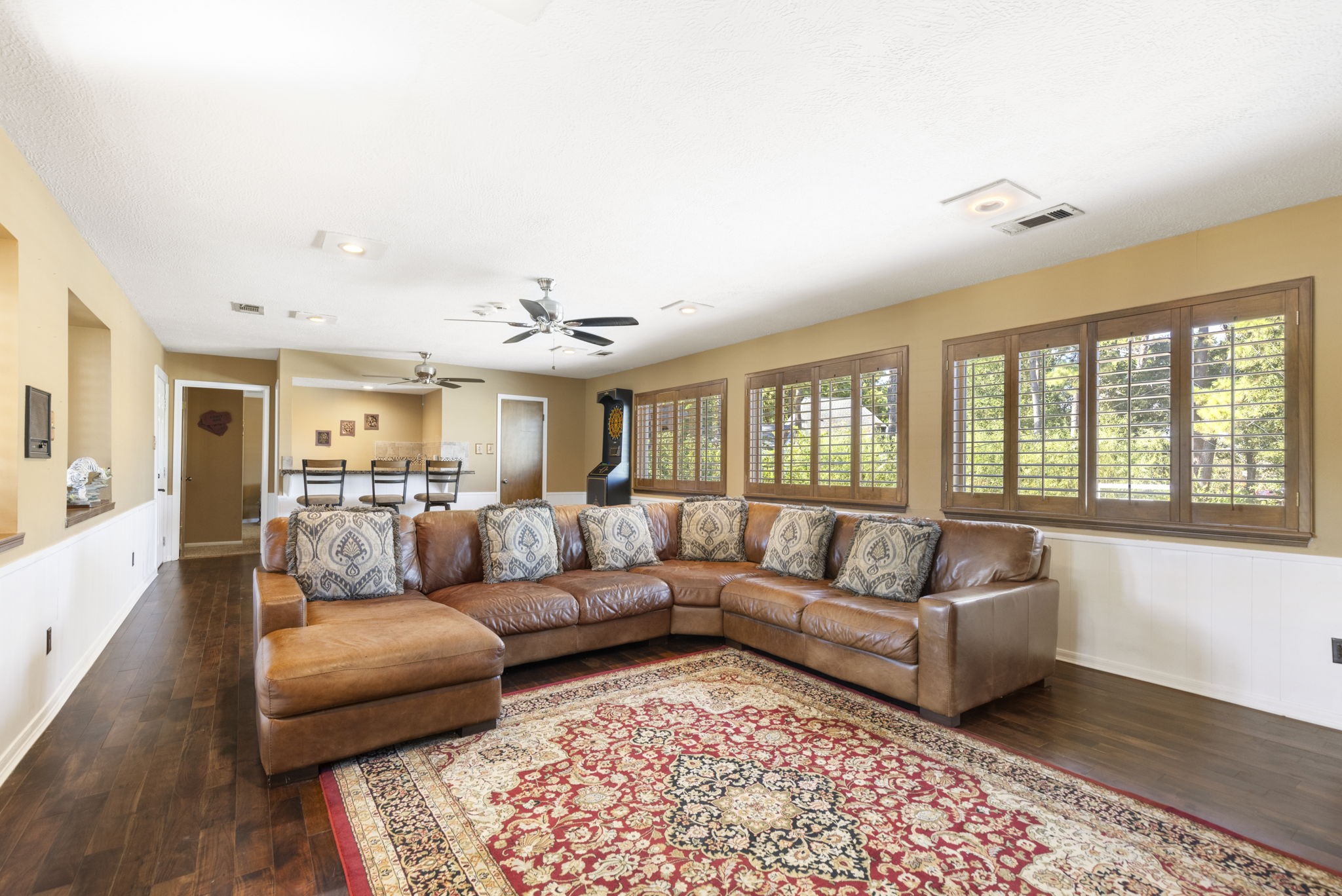 Upstairs boasts this incredible gameroom with walls of windows providing tree-top views, plantation shutters, tons of space for all your favorite activities and more.