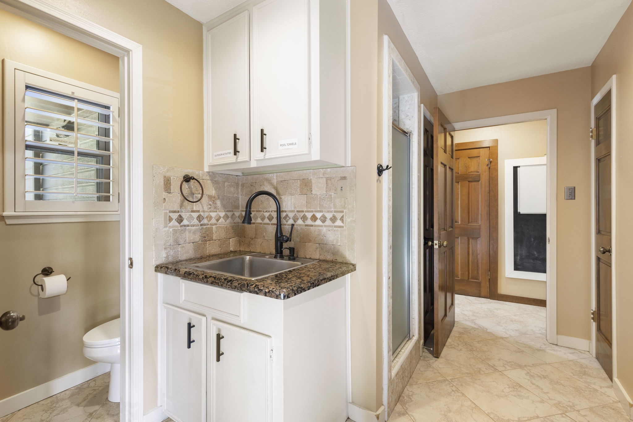 The utility room functions as a mud room with a half bathroom + shower (perfect as a pool shower), rinsing sink and great drop spaces.