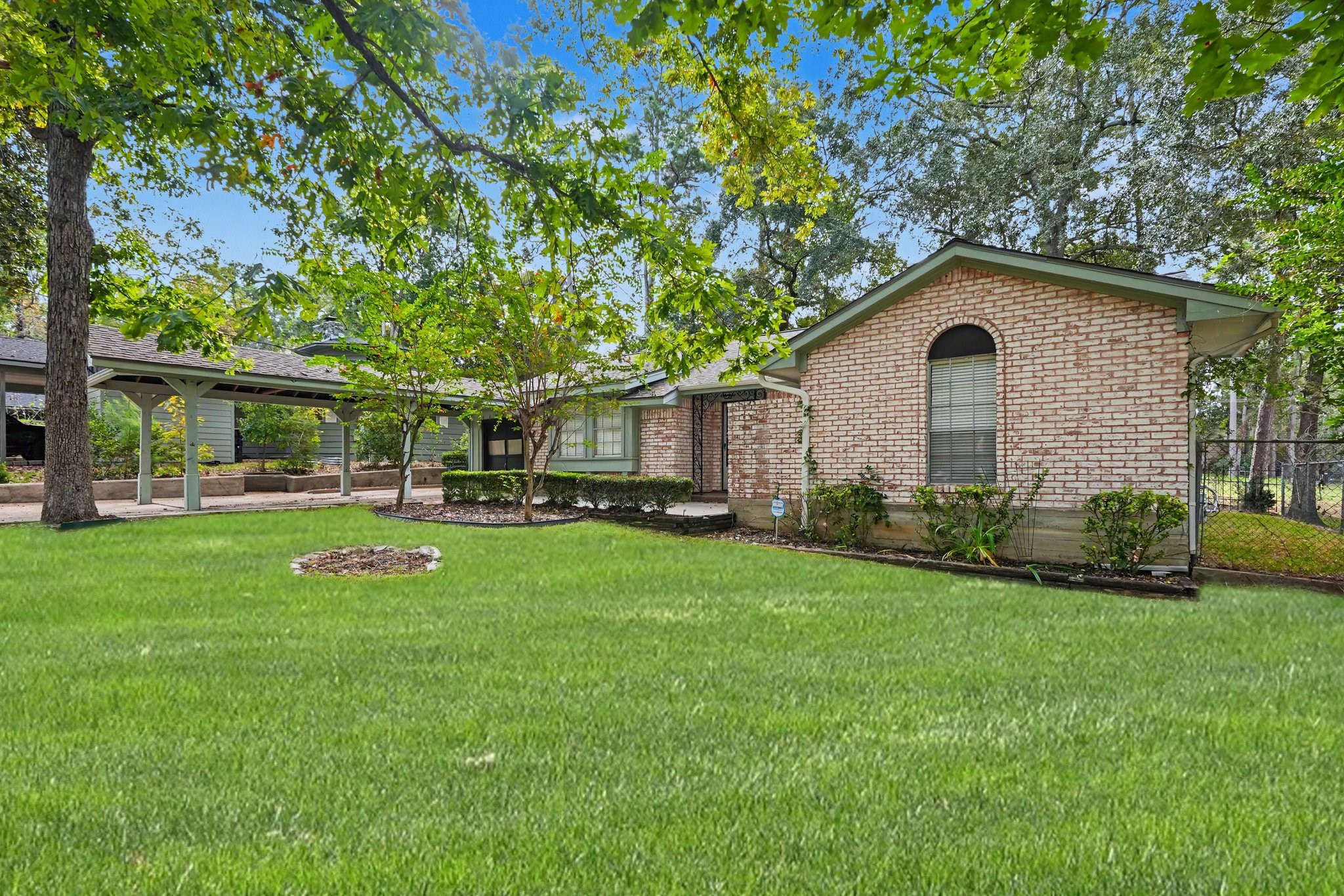This extended covered carport provides convenient additional parking leading directly to a garage with extra storage space.