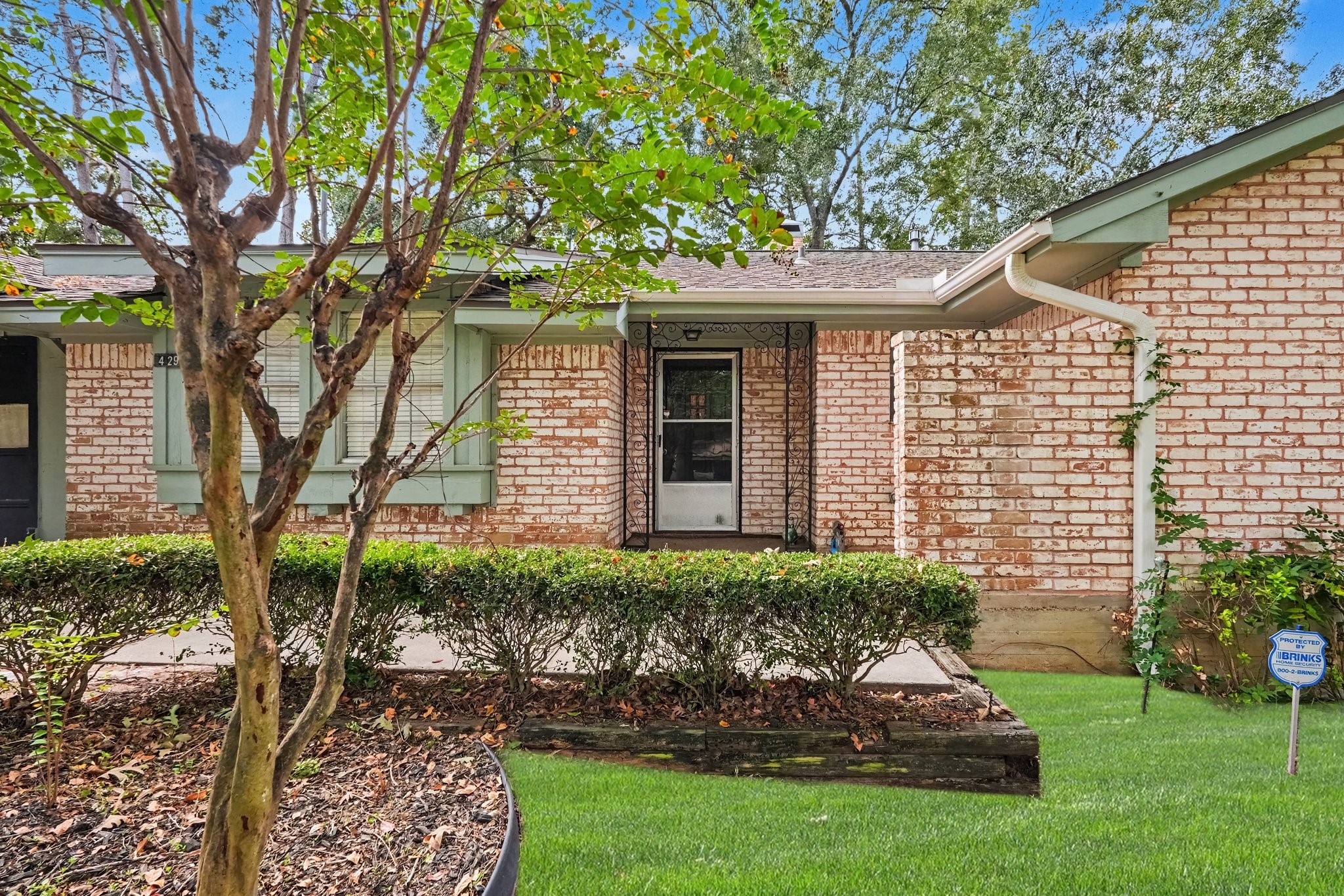 Spacious front patio tucked behind lush landscaping for added privacy, featuring a secure storm door paired with the main entry to allow for plenty of natural light.