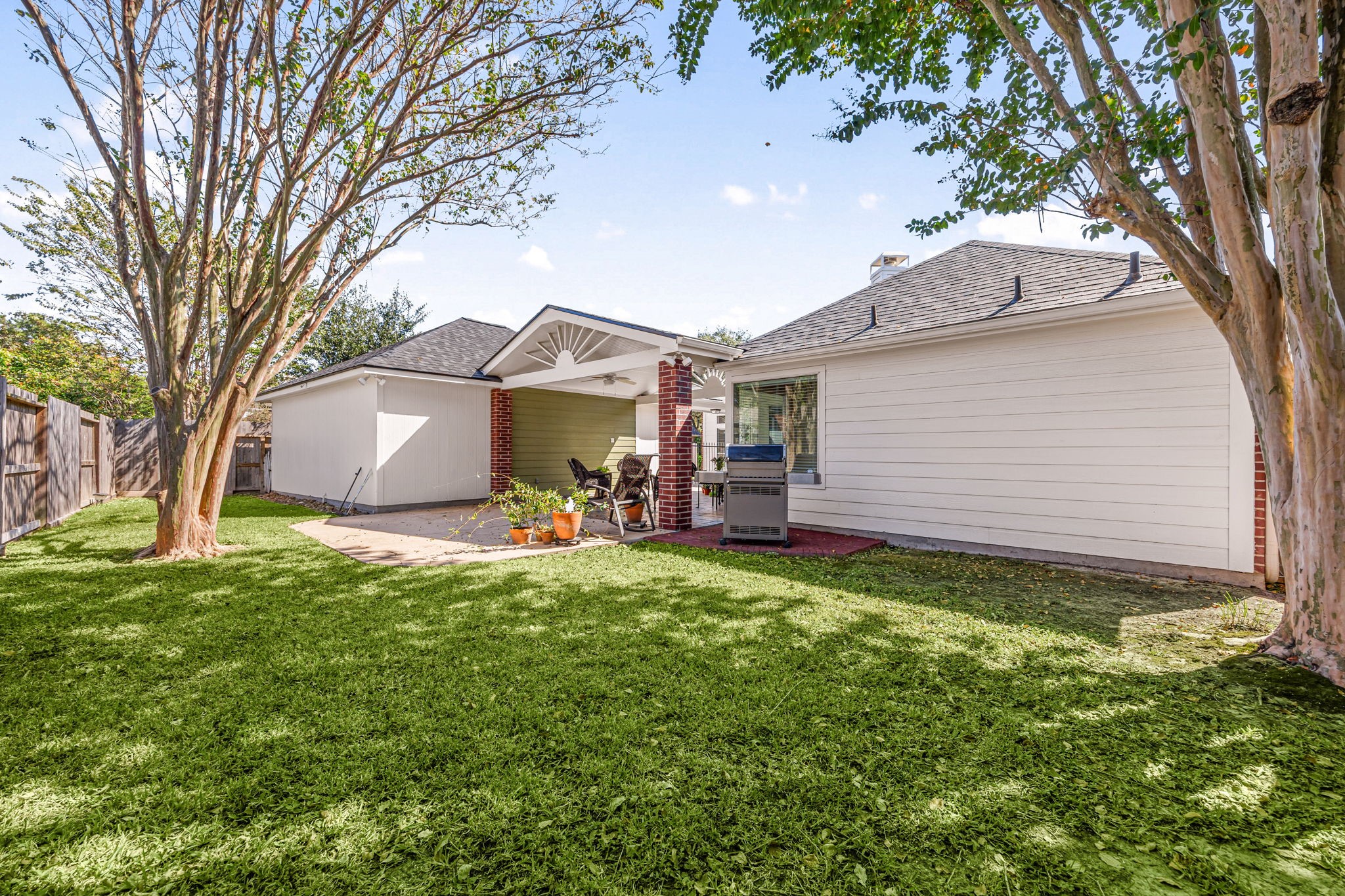 A spacious backyard surrounds the covered patio, with mature trees and an additional concrete slab offering even more room to entertain or grill.
