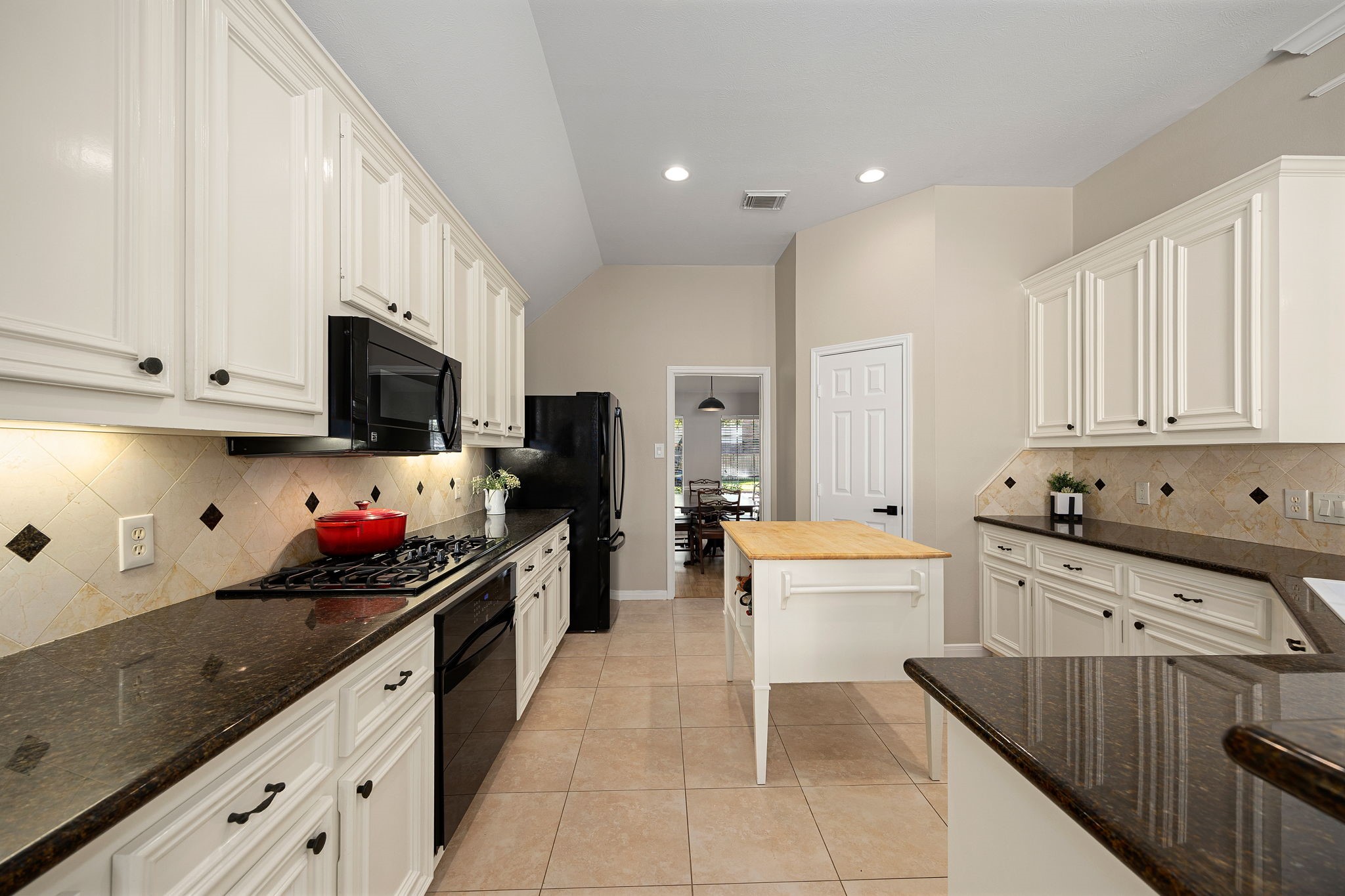 A gas cooktop, tiled backsplash, and under-cabinet lighting make this galley-style kitchen both functional and stylish. A gas cooktop, tiled backsplash, and under-cabinet lighting make this galley-style kitchen both functional and stylish.