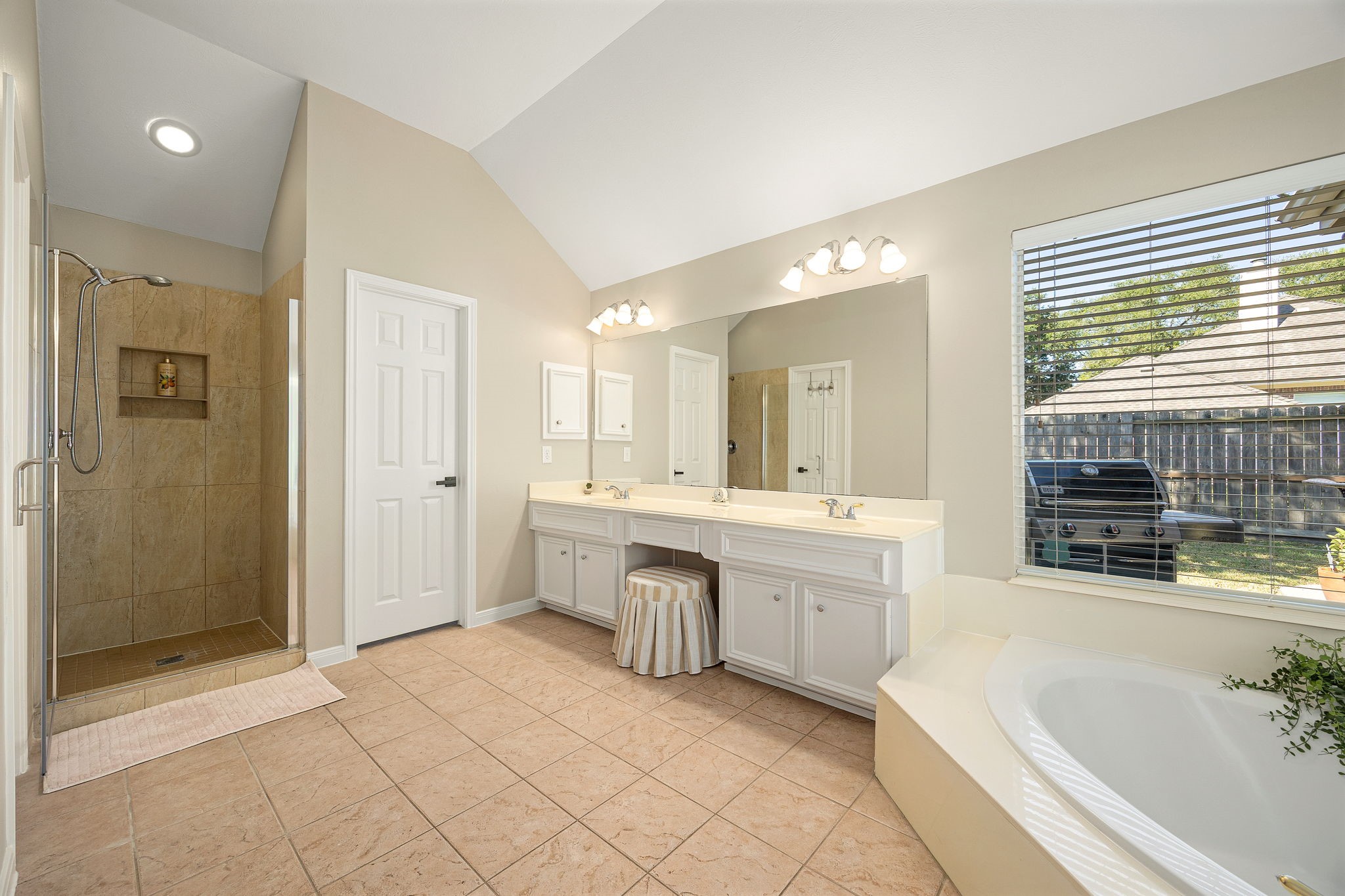 A separate walk-in tiled shower completes the spa-like primary bath, with the soaking tub visible just beyond.