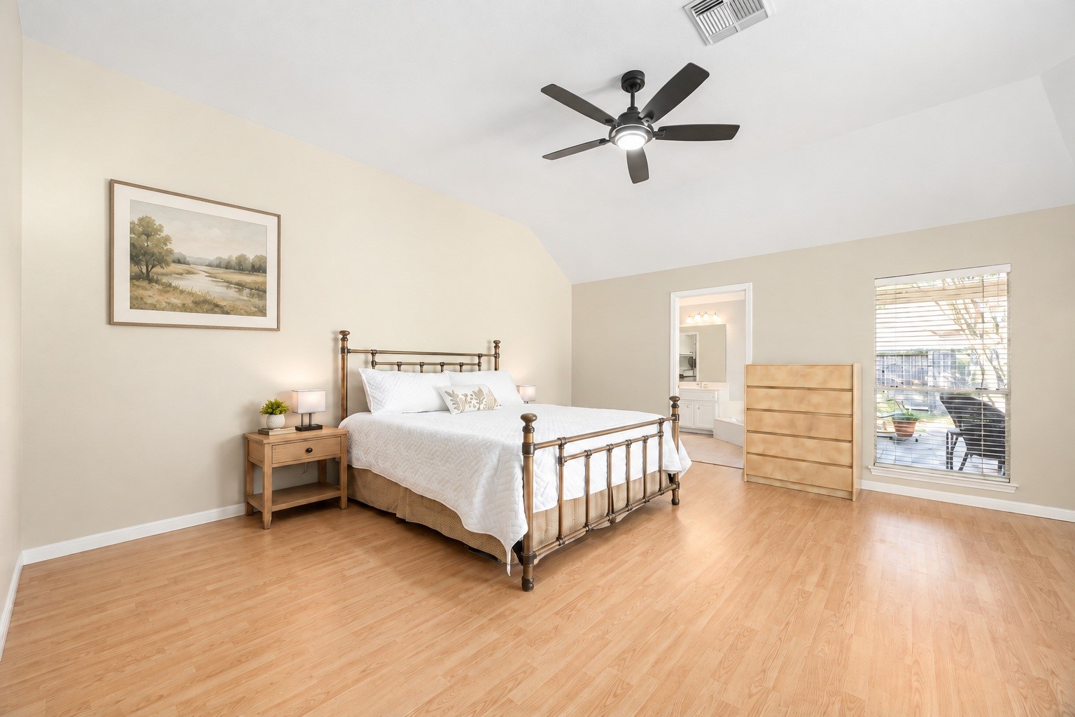 The primary bedroom impresses with a vaulted ceiling and large windows overlooking the backyard patio, creating a bright and relaxing retreat. Virtually staged.