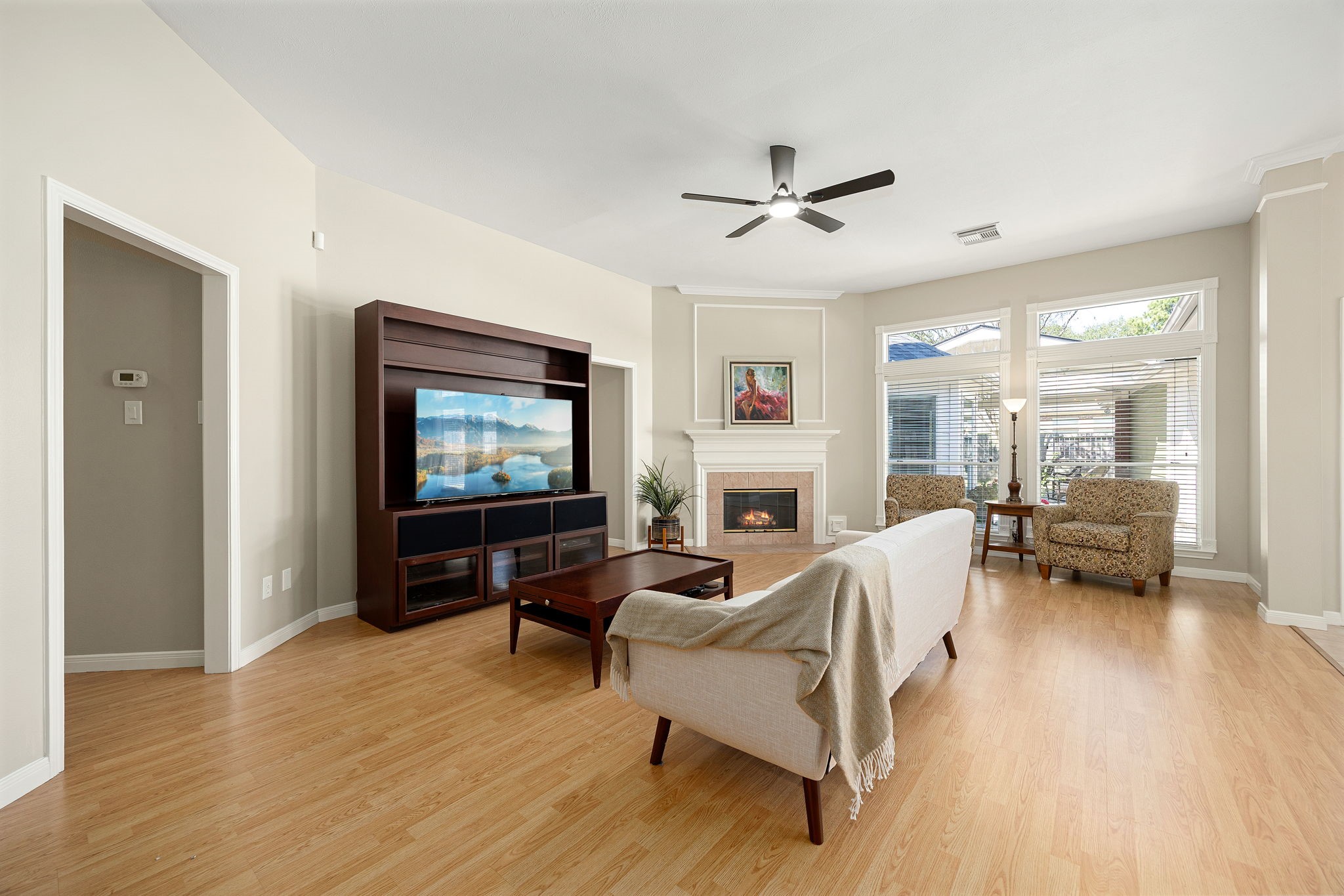The living area centers around a cozy corner fireplace, complete with a ceiling fan and large windows that bring in plenty of natural light. The living area centers around a cozy corner fireplace, complete with a ceiling fan and large windows that bring in plenty of natural light.