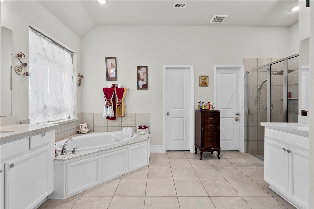 The primary en-suite bath offers dual vanities, a walk-in shower, soaking tub and custom walk-in closet