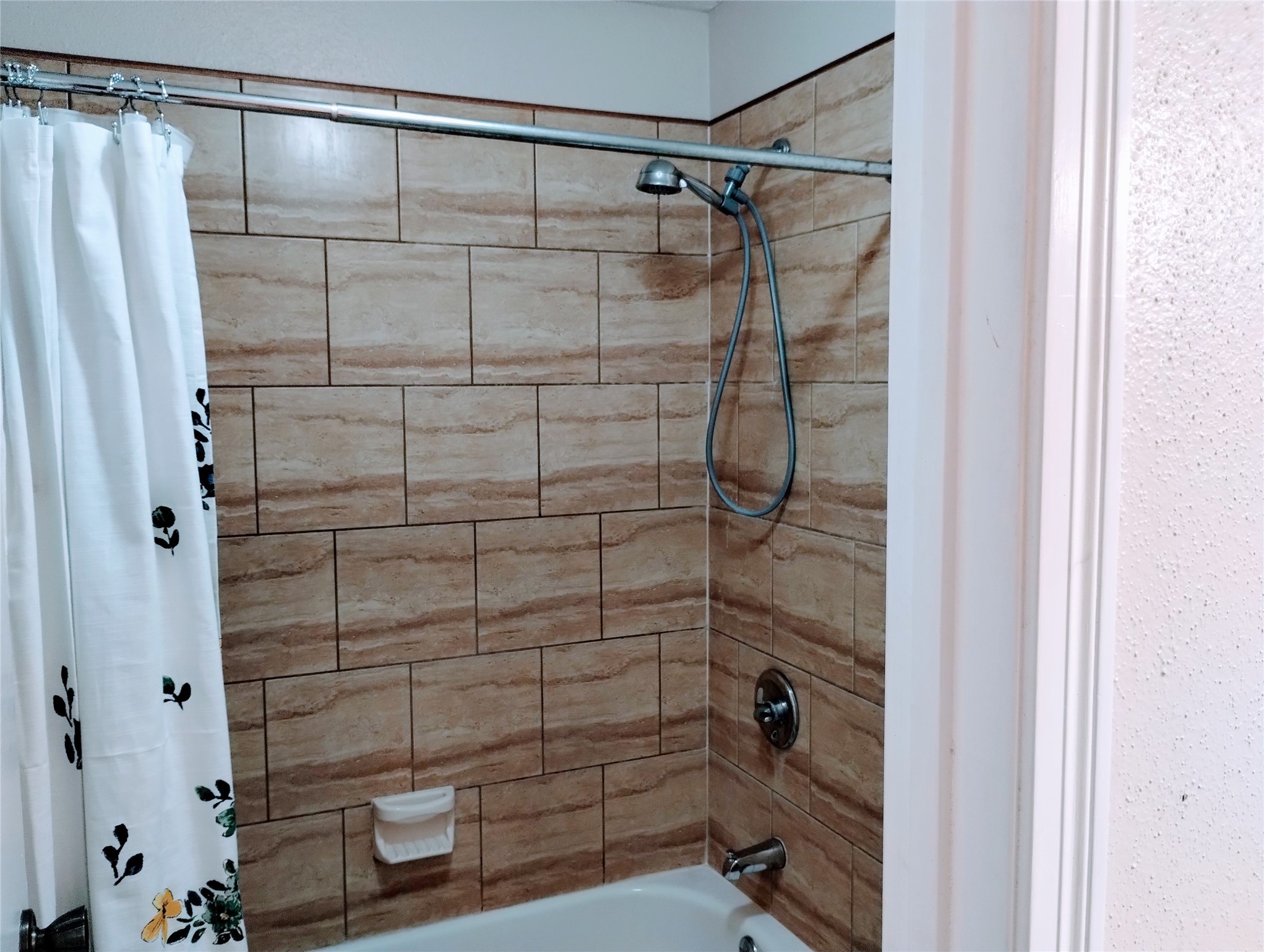 The TUB/SHOWER has a tile surround and a stable or handheld shower wand.