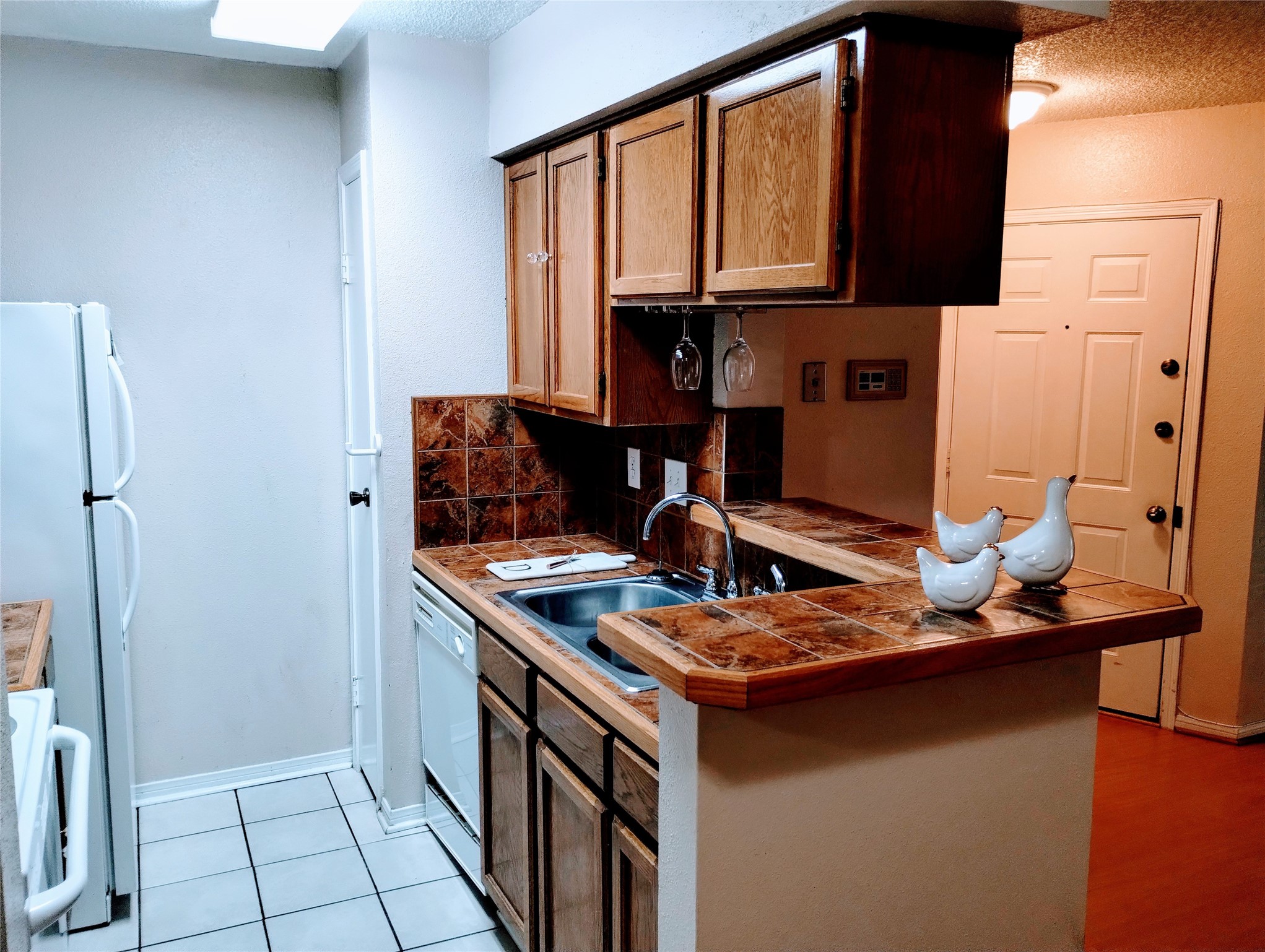 Another view of the KITCHEN showcases the double stainless sink and the pantry to the left of the dishwasher.  Notice the FRONT DOOR in the Foyer.