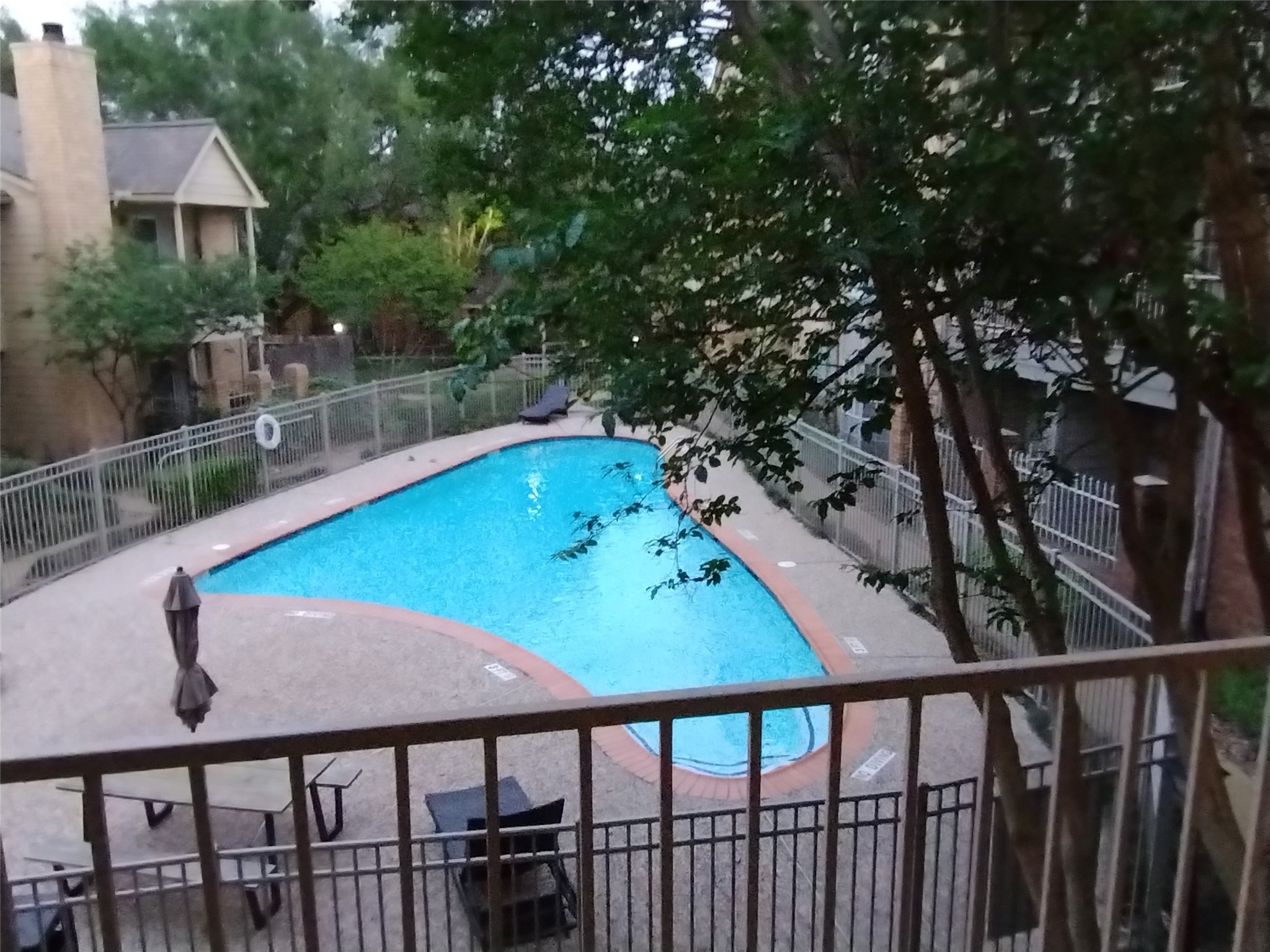 Enjoy delightful views from the BALCONY TERRACE of 11201 LYNBROOK DR. #3807 of a lovely pool with wrought iron security fencing and mature trees.  Ample space on the Balcony for outdoor furniture.