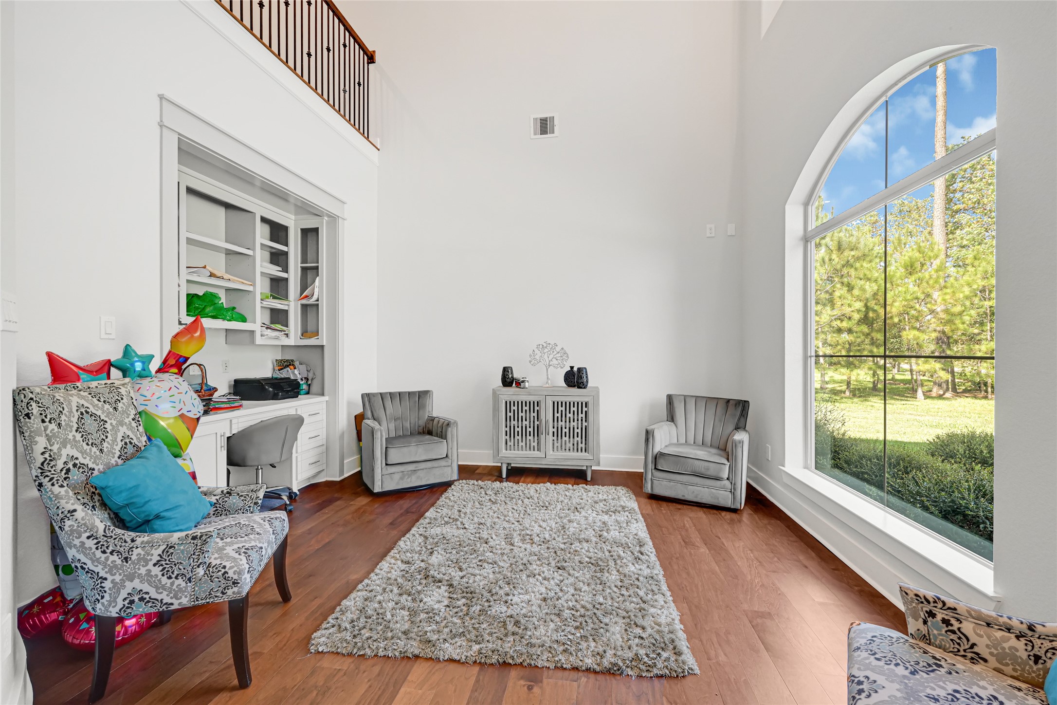 Bright sitting area with a large arched window and wood flooring.