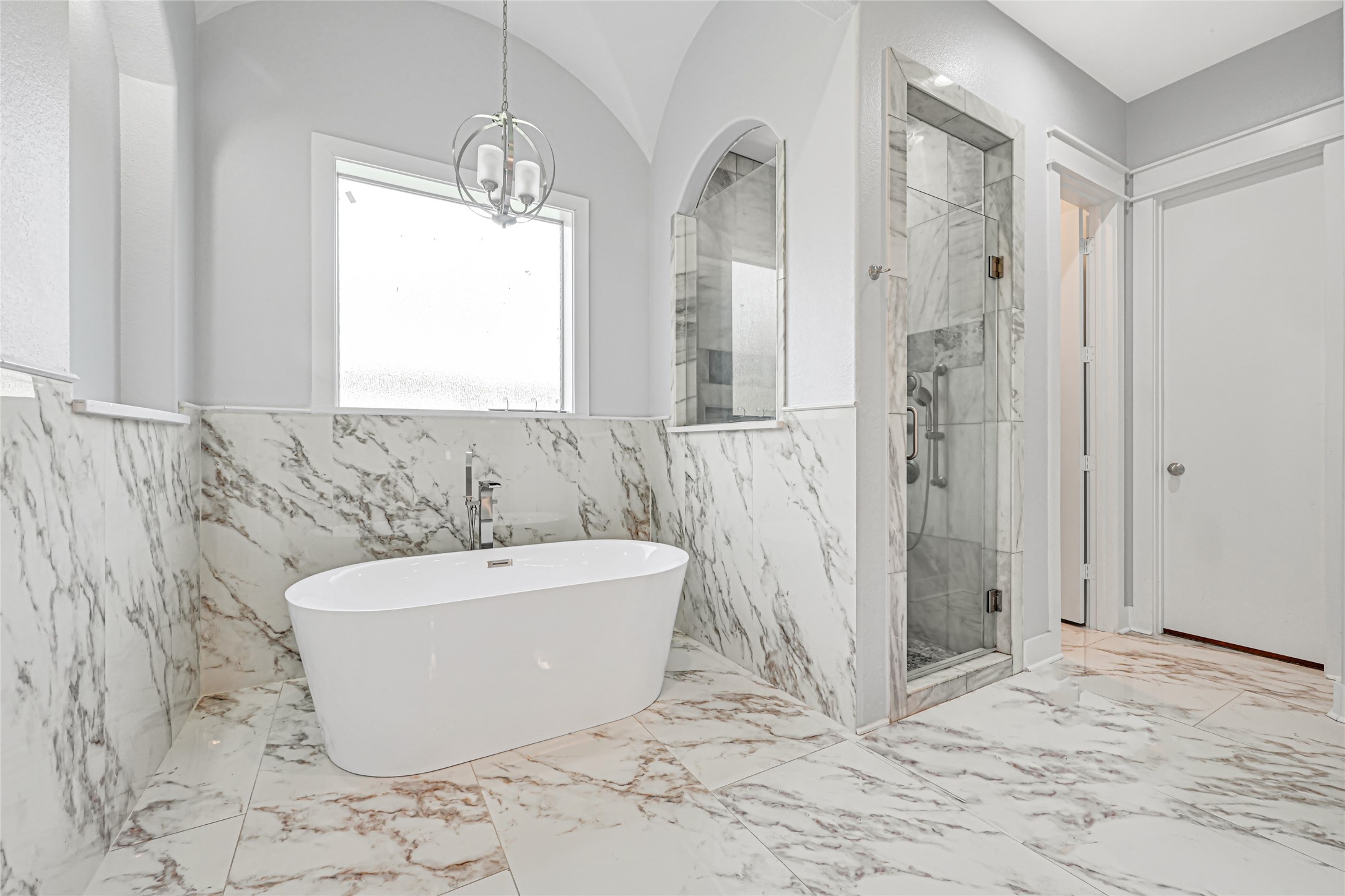Freestanding soaking tub and separate glass-enclosed shower create an inviting retreat.