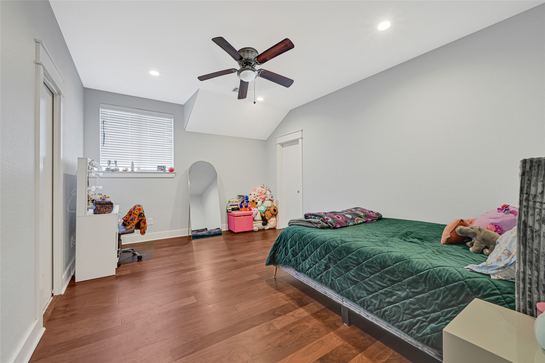 Generous bedroom with wood flooring, a ceiling fan, and room for additional seating.