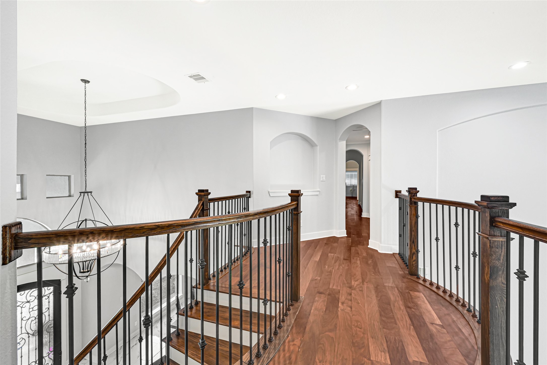 Bright sitting area with a large arched window and wood flooring.